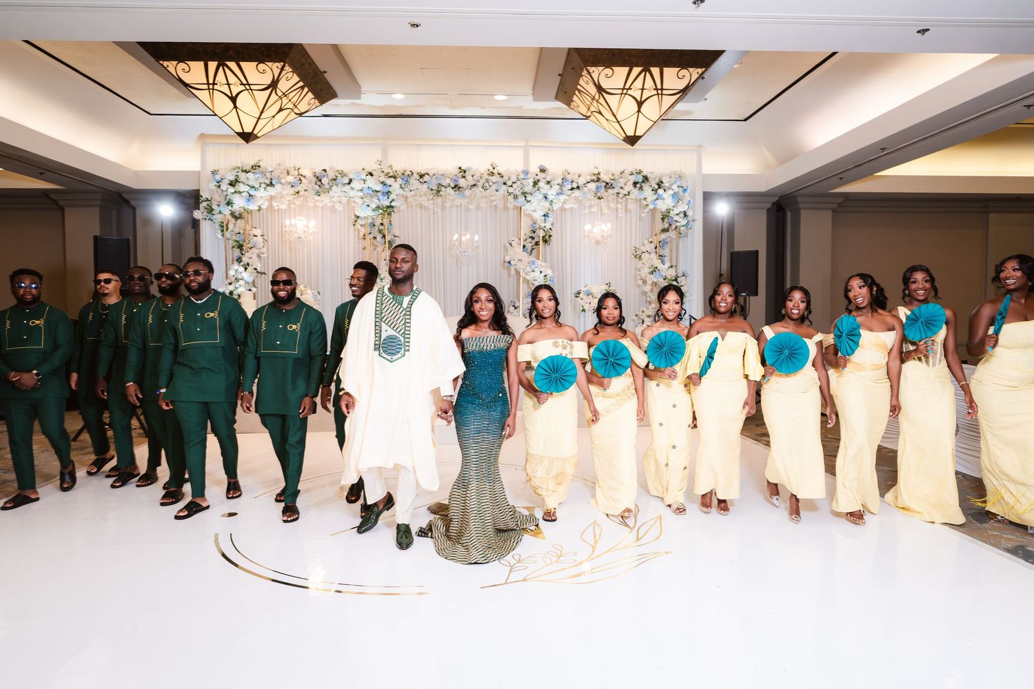 Wedding party members lined up in formal attire with teal and white colors in an elegant venue.