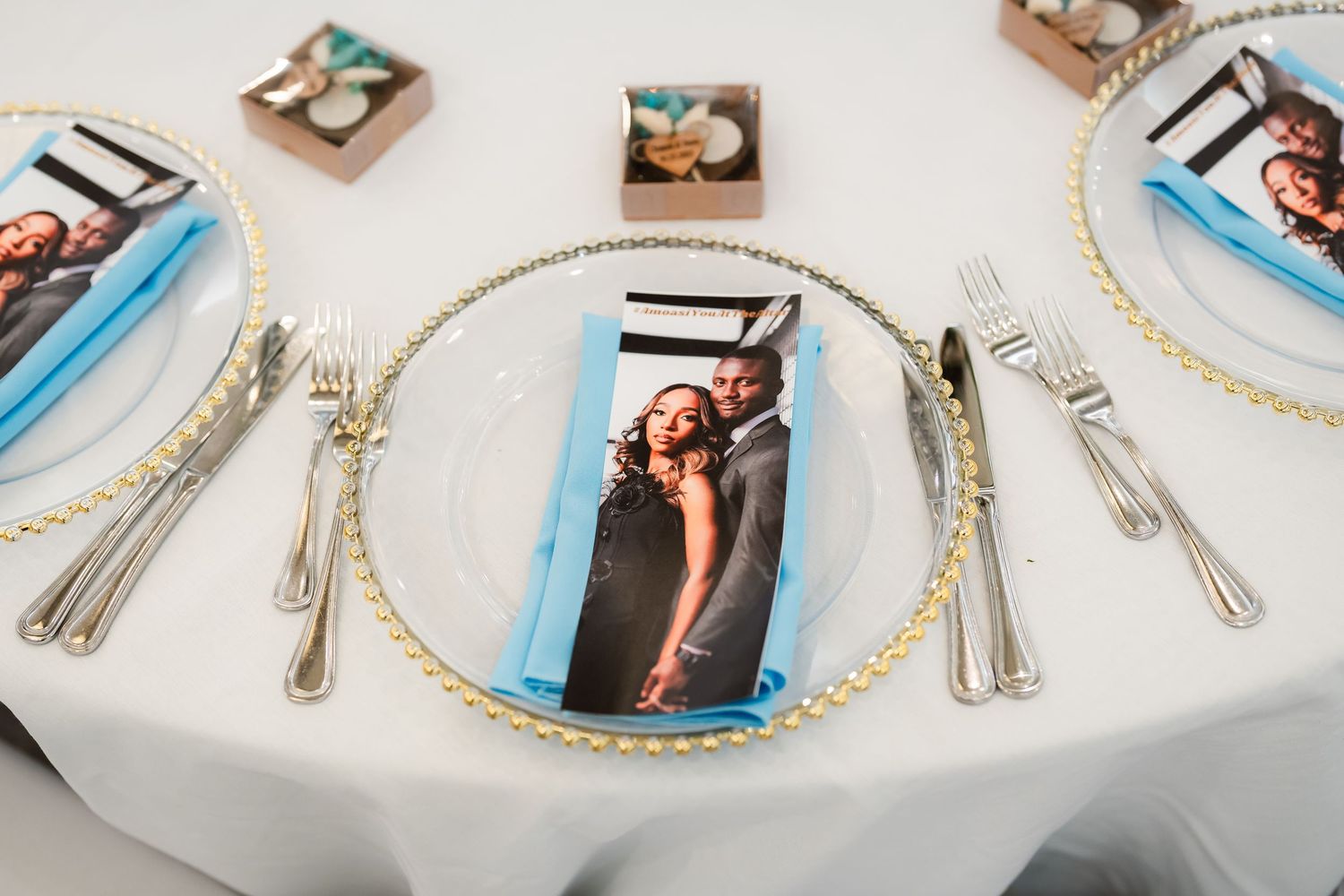 Wedding place setting with gold-rimmed charger plate, personalized photo favors, and elegant silverware.