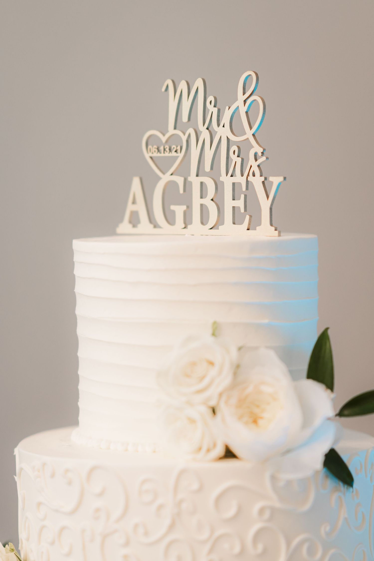 Elegant white wedding cake with Mr & Mrs topper and delicate rose decorations.
