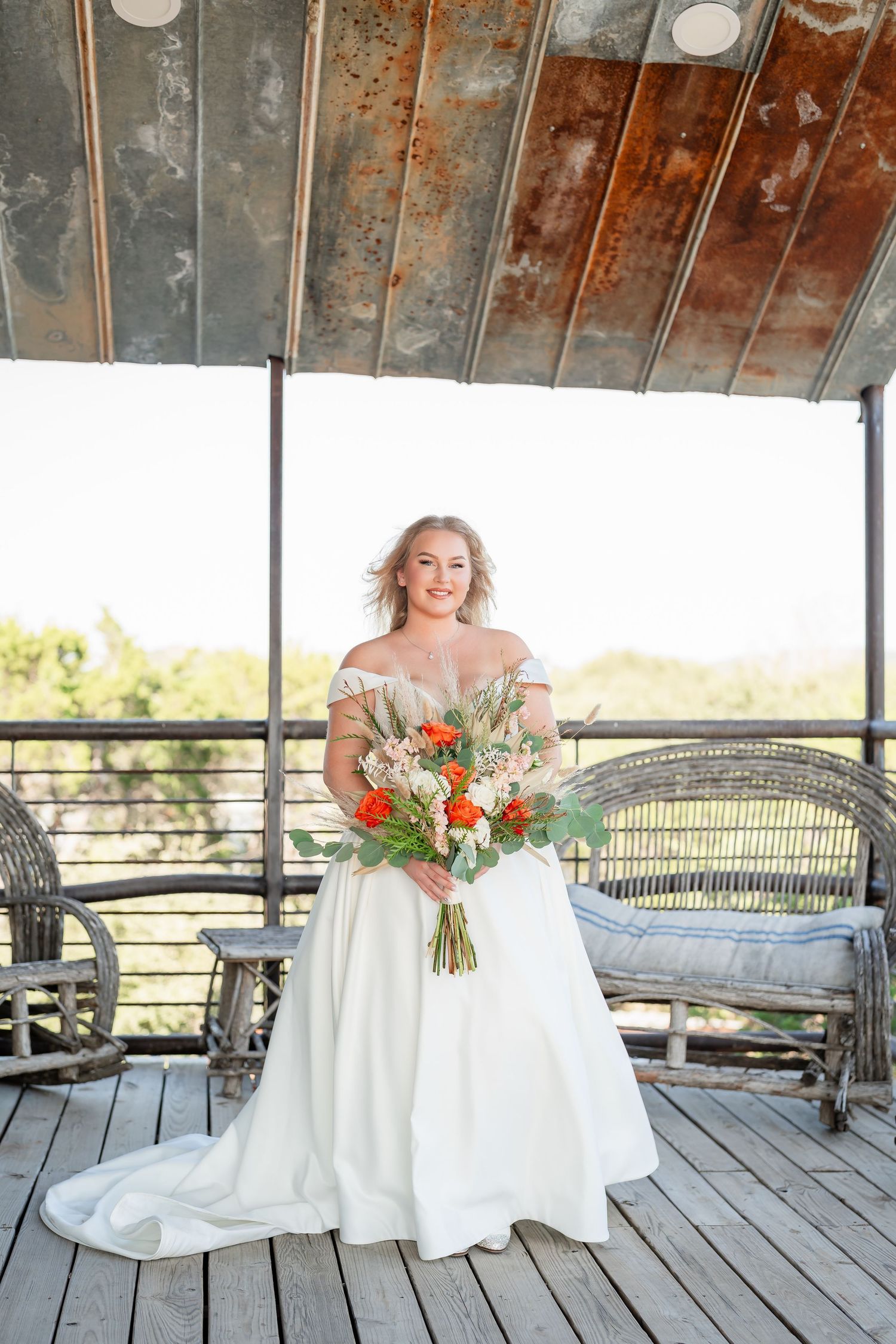 Rustic wooden deck wedding venue with vintage furniture and metal roof details.