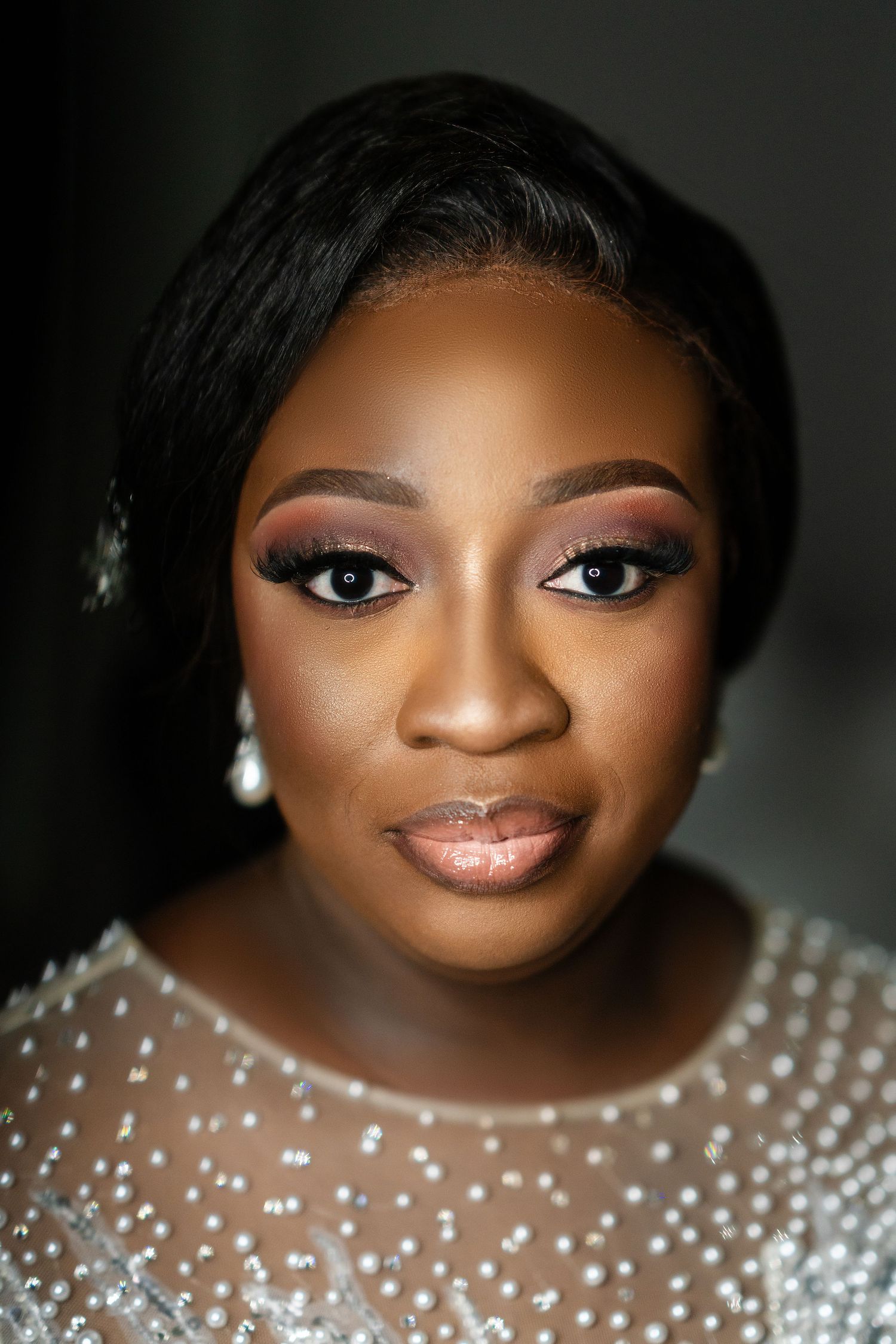 Stunning bridal beauty shot featuring glamorous makeup and pearl-embellished gown details.