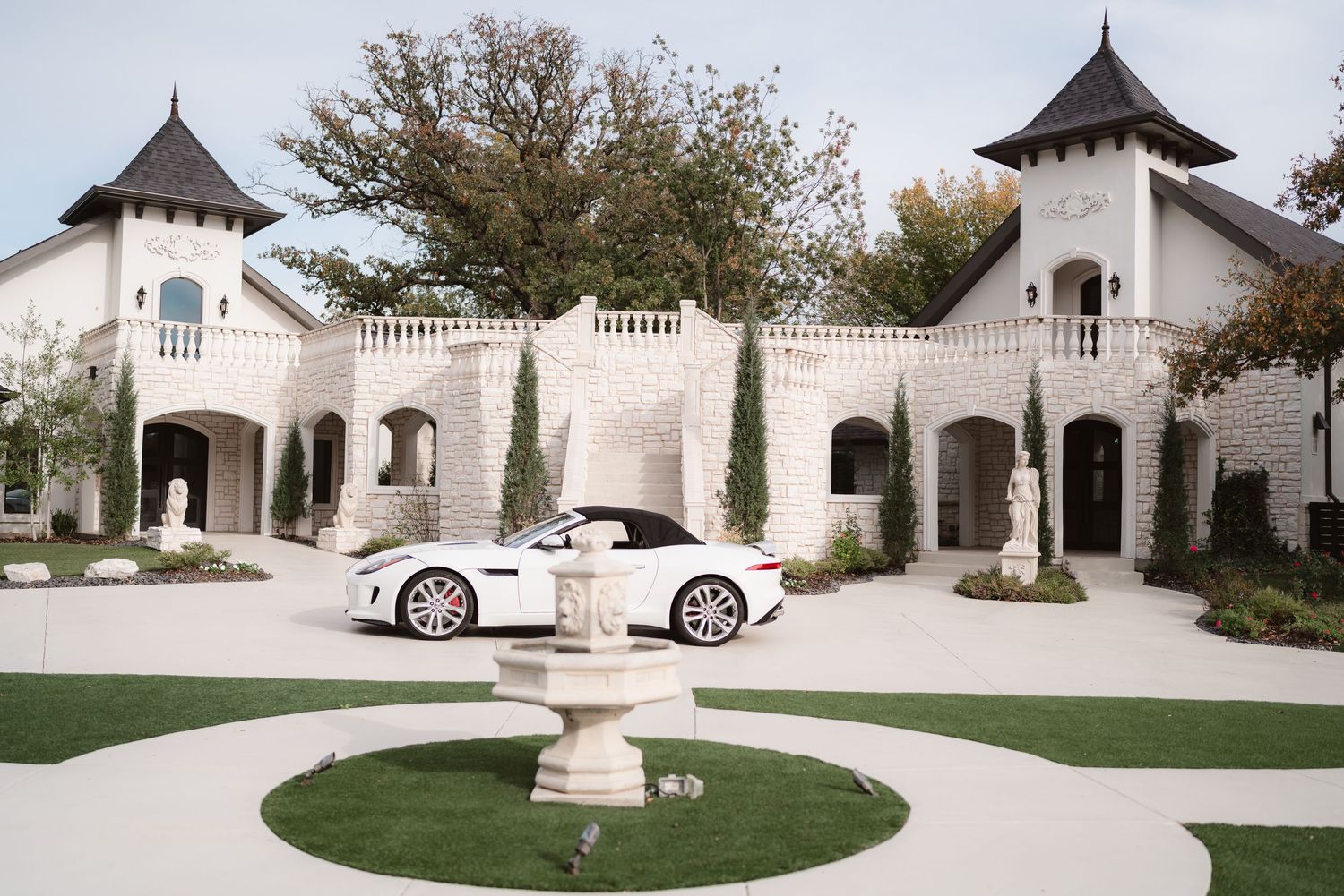 White wedding chapel with turrets and elegant architectural details sits nestled among trees in a serene garden setting.