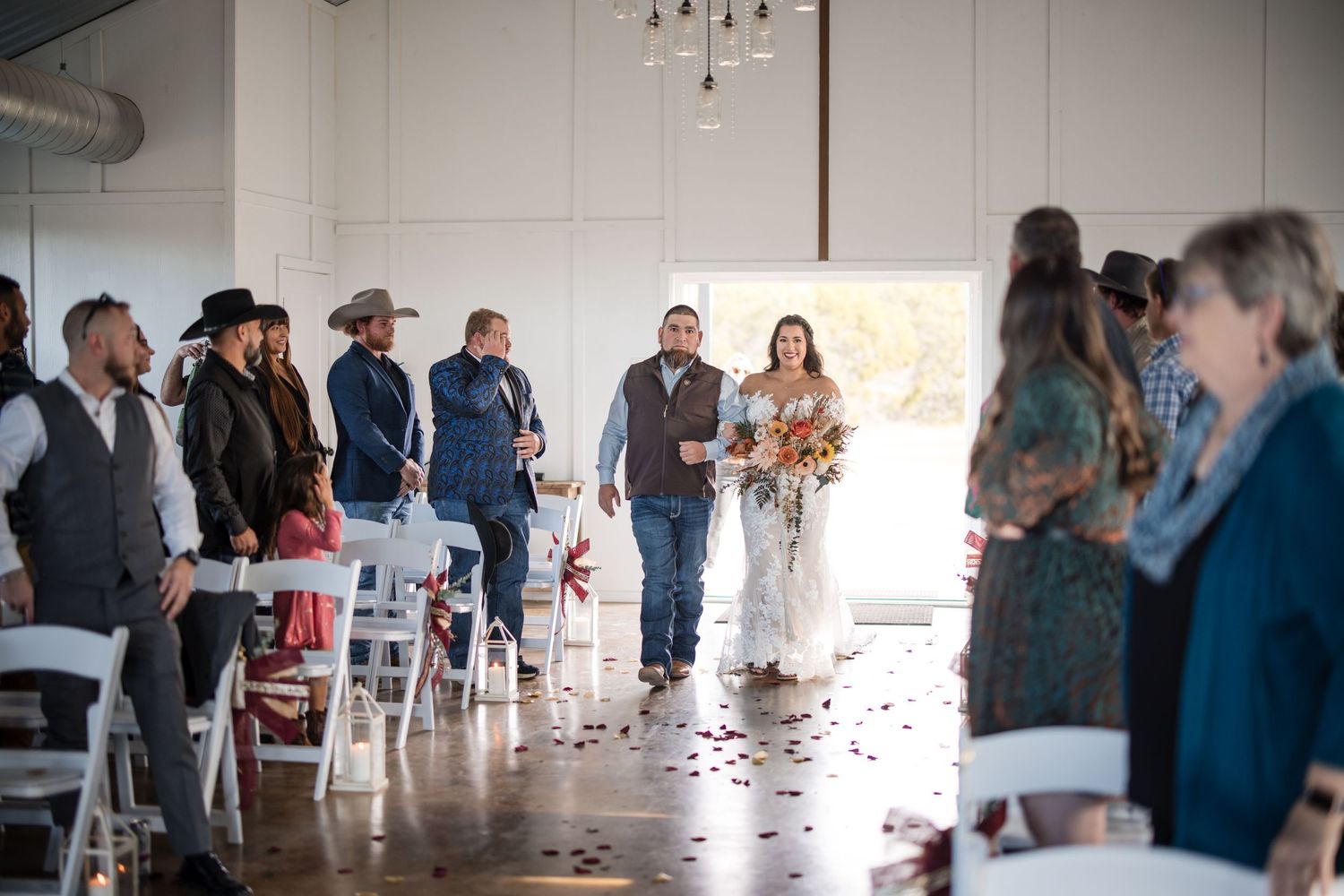 Wedding reception candid moments captured inside a bright white rustic venue space.