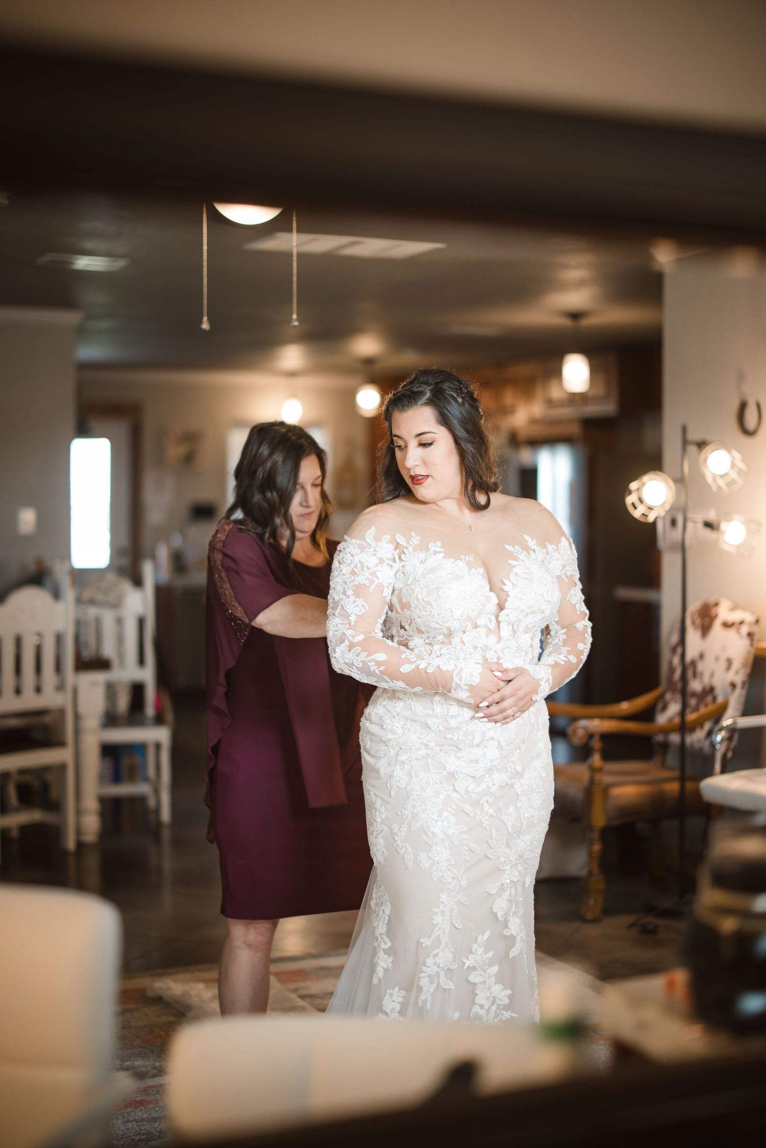 Elegant lace wedding dress details shown in indoor venue with warm lighting.