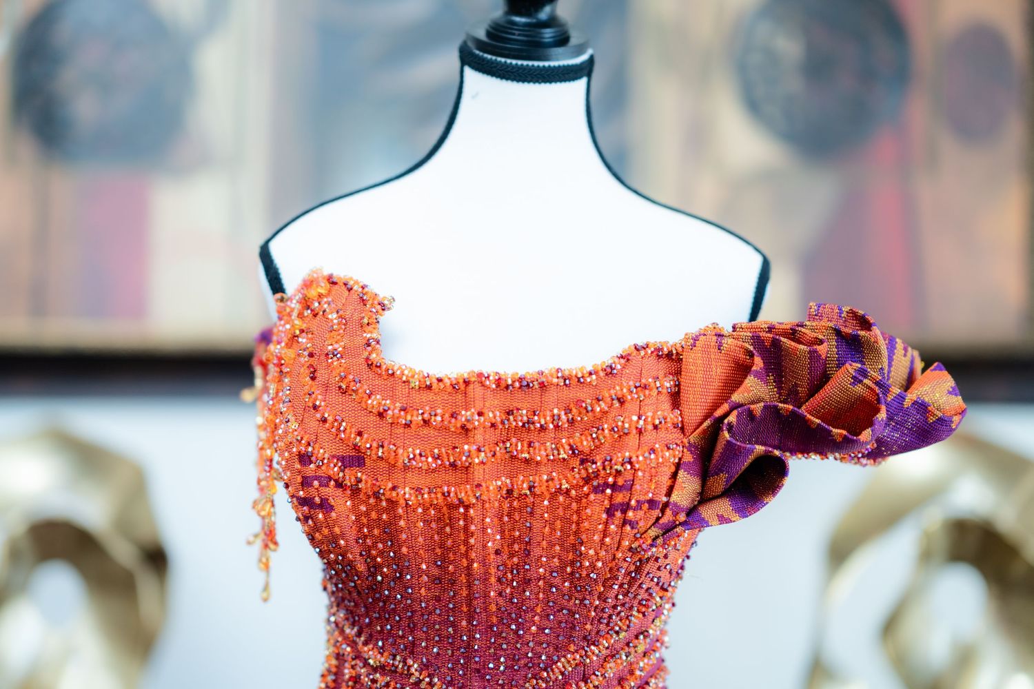 Close-up detail of an intricately beaded red and orange bodice with sparkly embellishments.