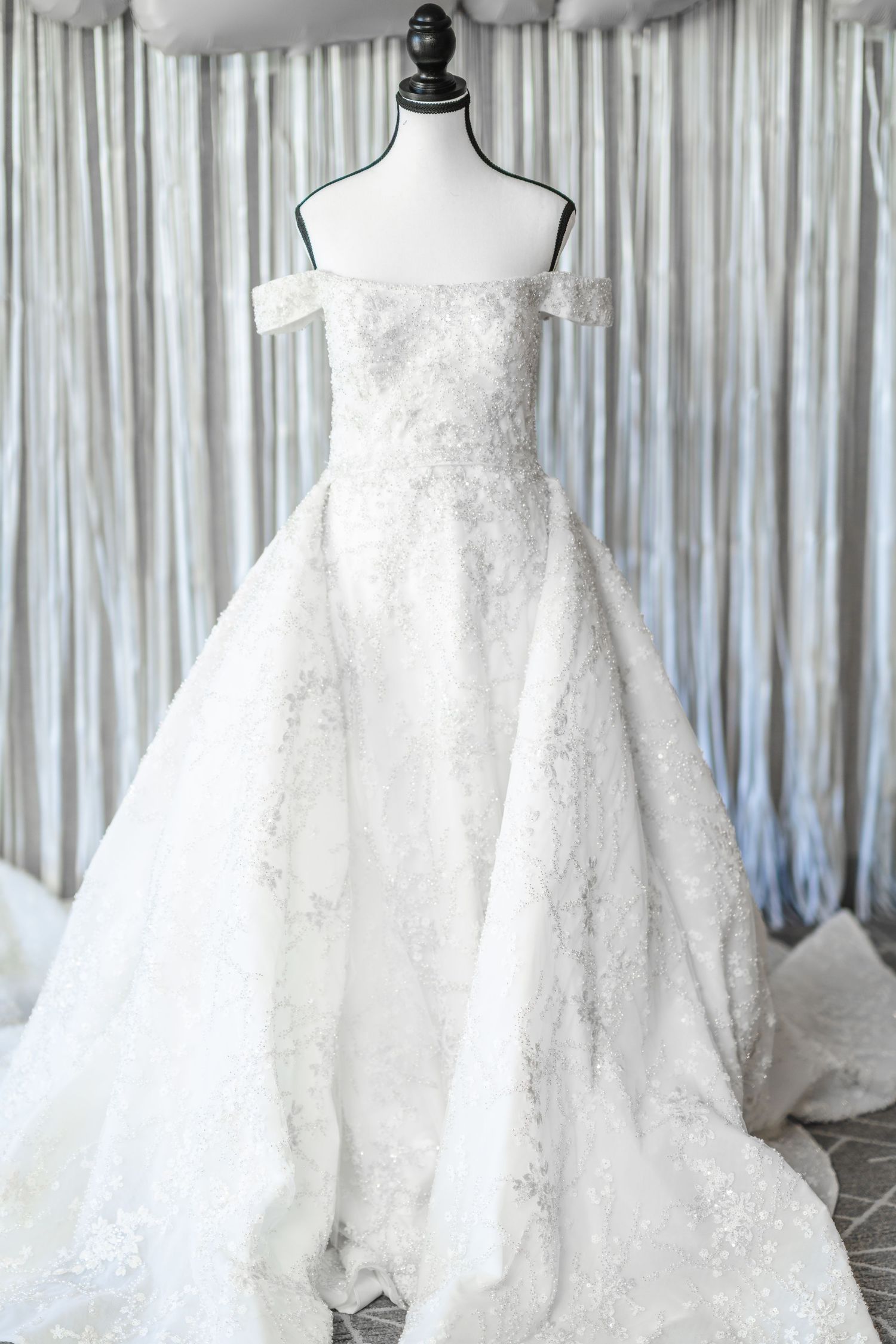 Elegant white wedding dresses displayed on mannequins in a bridal boutique with draped fabric backdrop.