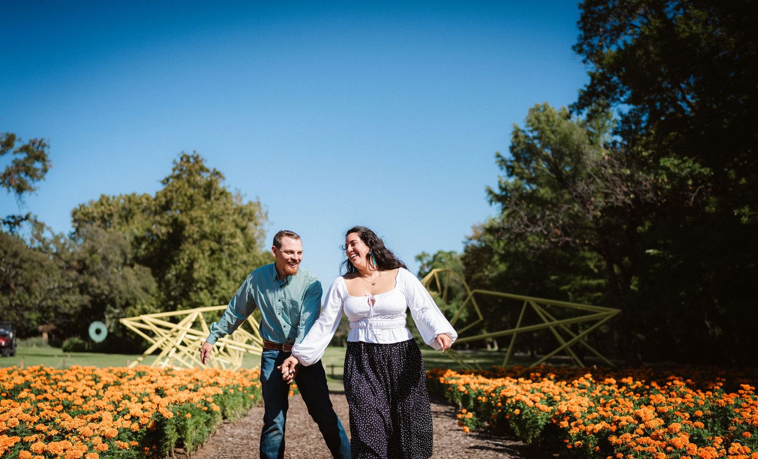 A couple enjoys a romantic moment together in a vibrant orange pumpkin patch on a sunny autumn day.
