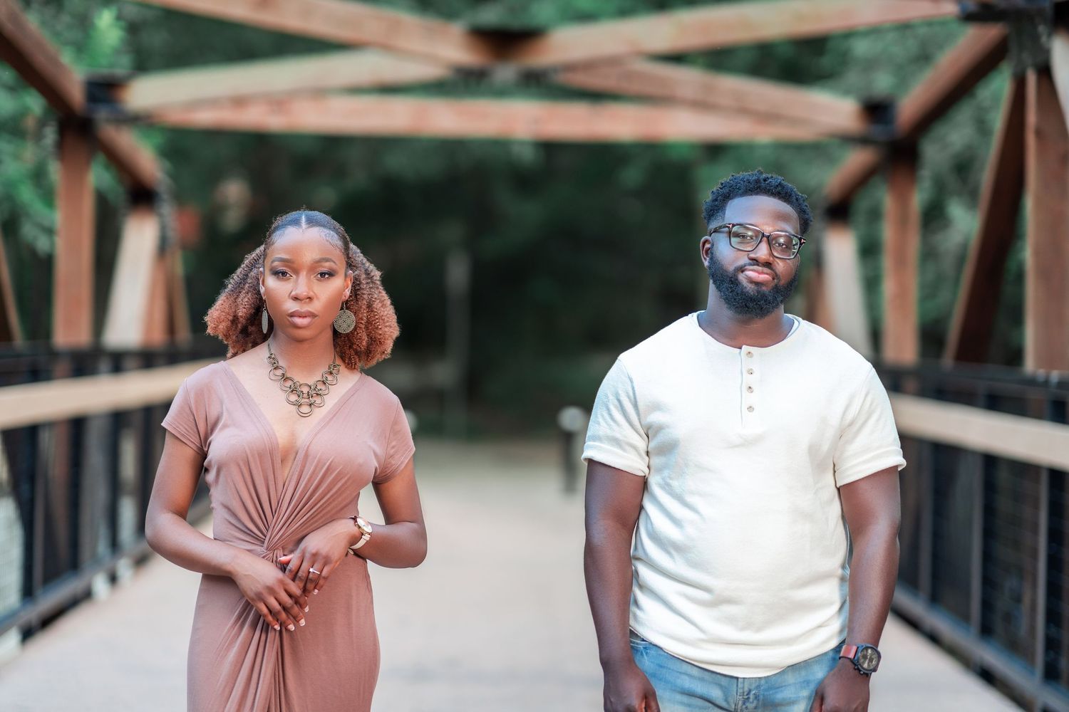 A couple walks together on a wooden bridge during a casual photoshoot.