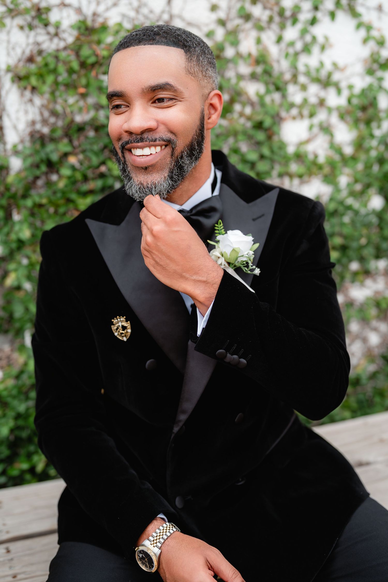 Groom in classic black tuxedo smiles warmly during wedding portraits.