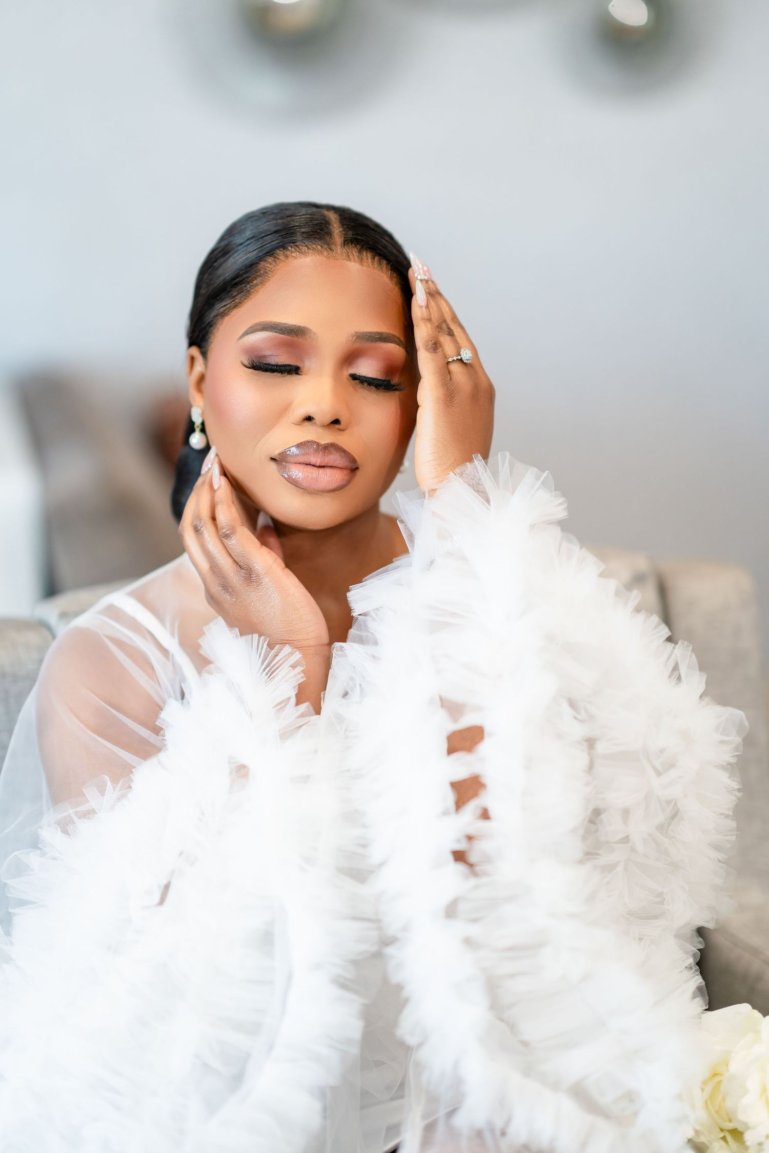 Glamorous bridal portrait featuring a soft white feather wrap and elegant makeup in a dreamy setting.