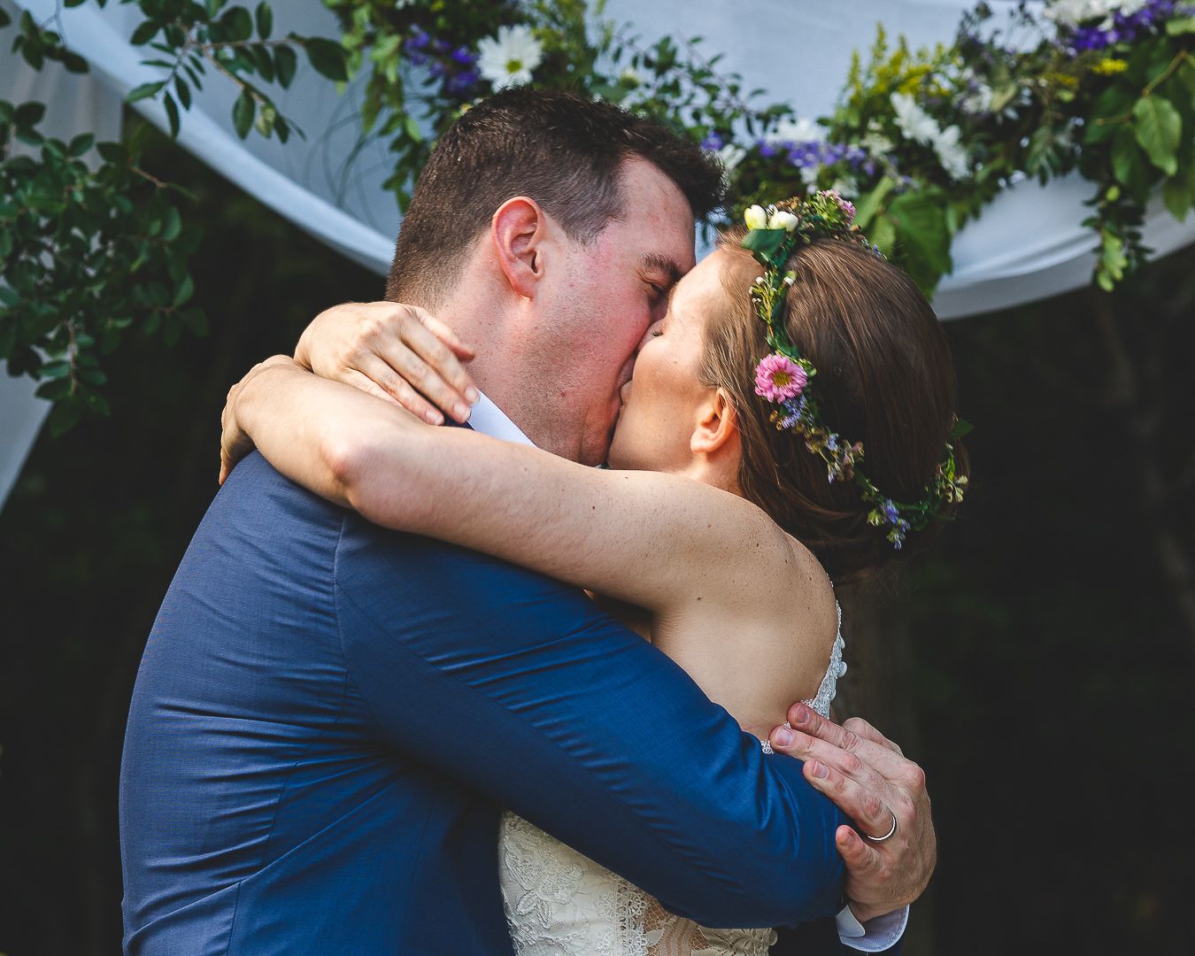 A romantic kiss shared during an outdoor wedding ceremony.
