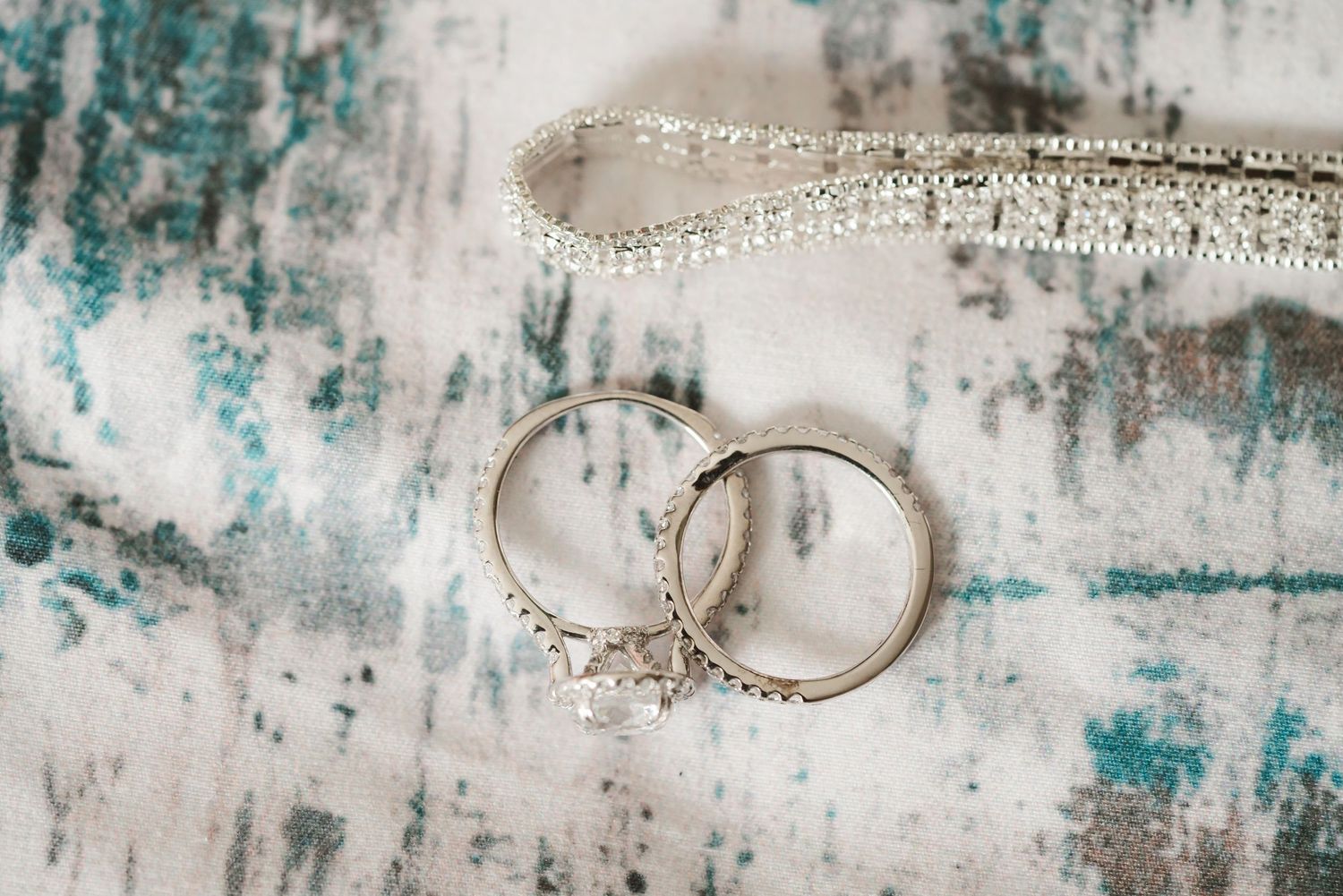 Close-up of elegant wedding rings on textured turquoise and white background.