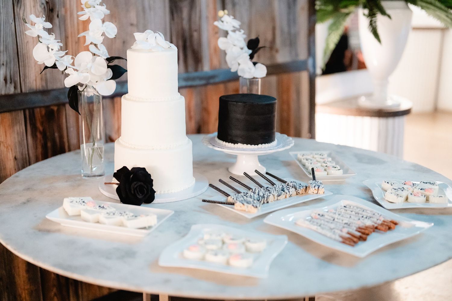 Wedding dessert table with white cake and treats decorated with orchids in an elegant setting.