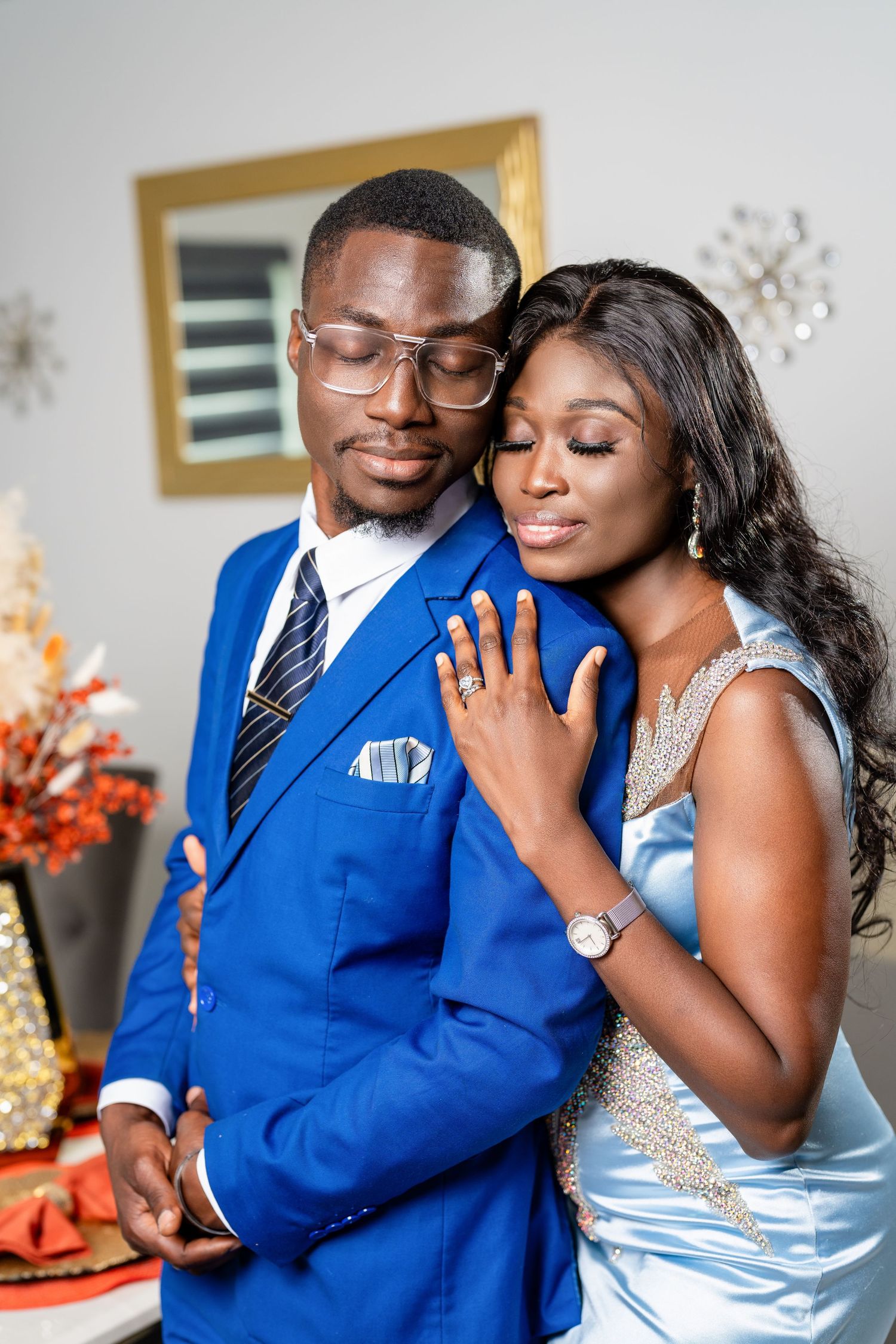 A couple in coordinated blue and silver outfits share intimate moments in a romantic indoor photoshoot.