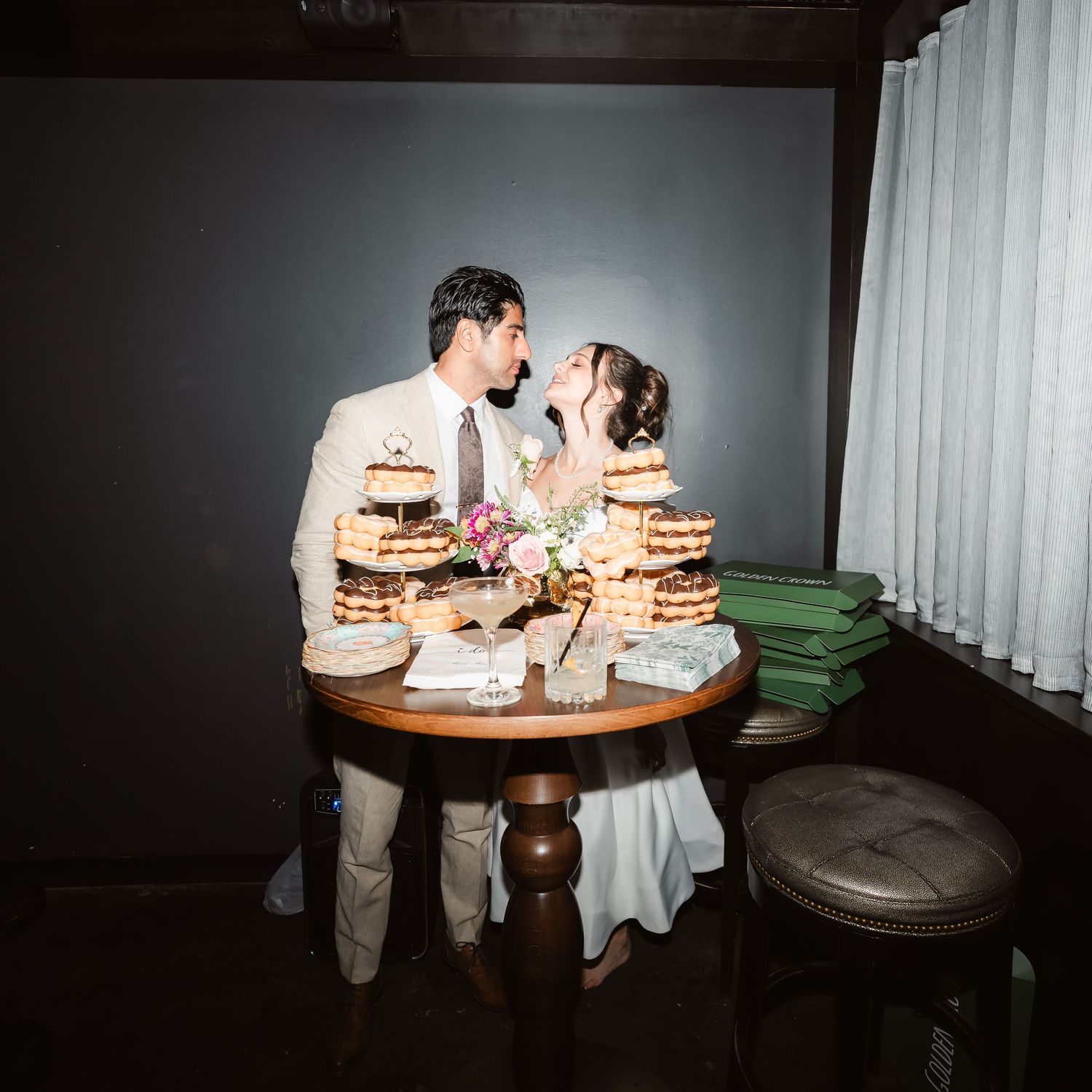 Wedding reception table settings with candlelight and floral centerpieces in a dark room.