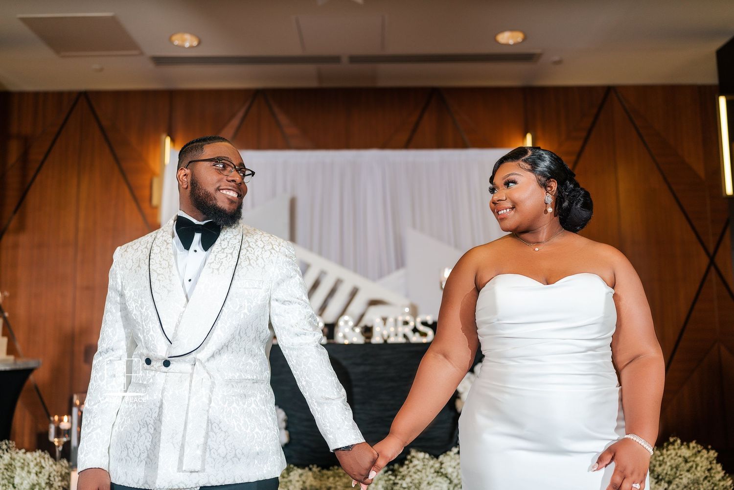 Wedding reception setup with white decor and elegant table settings.