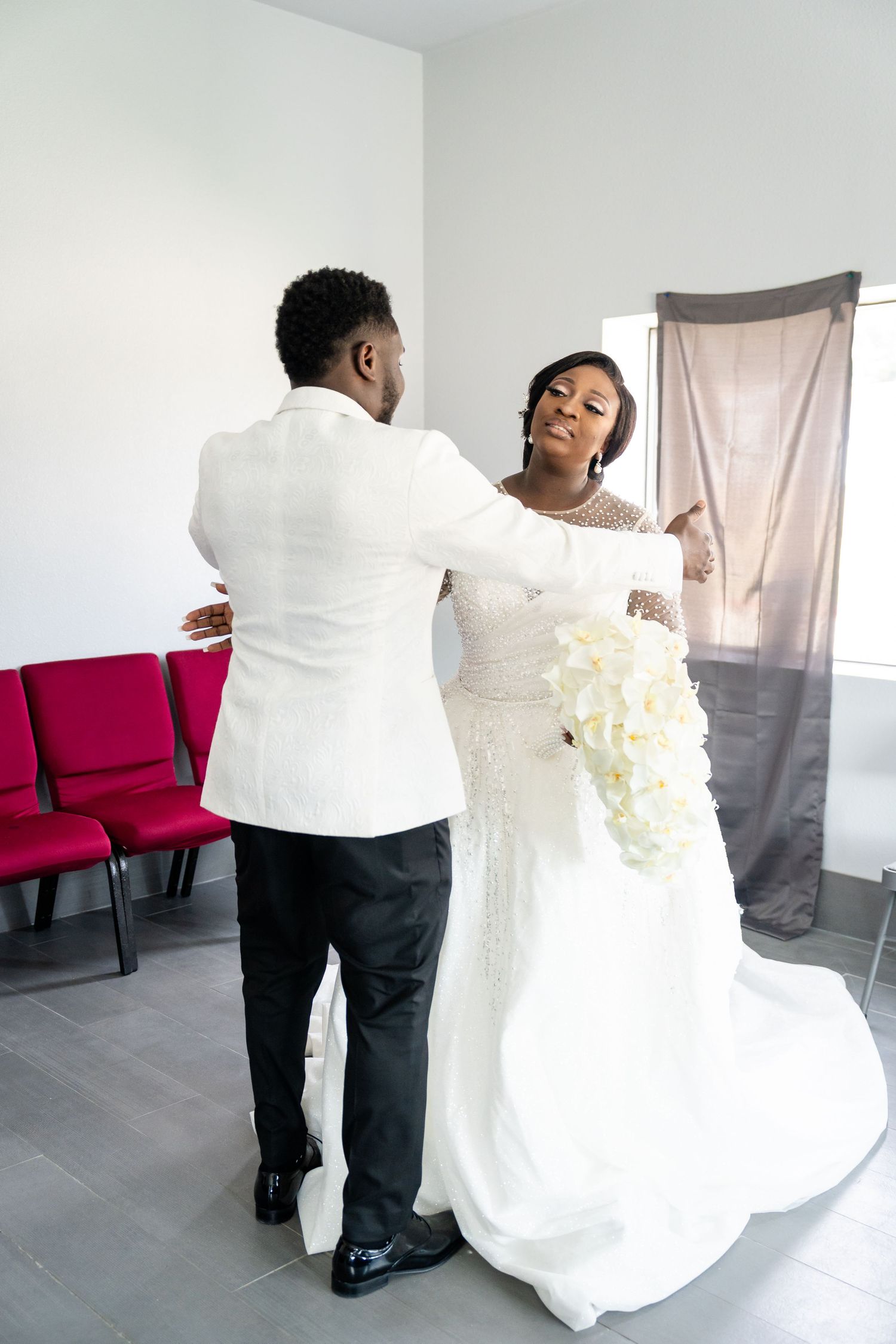 Wedding photoshoot showing a white bridal gown and formal attire in a minimalist indoor setting.