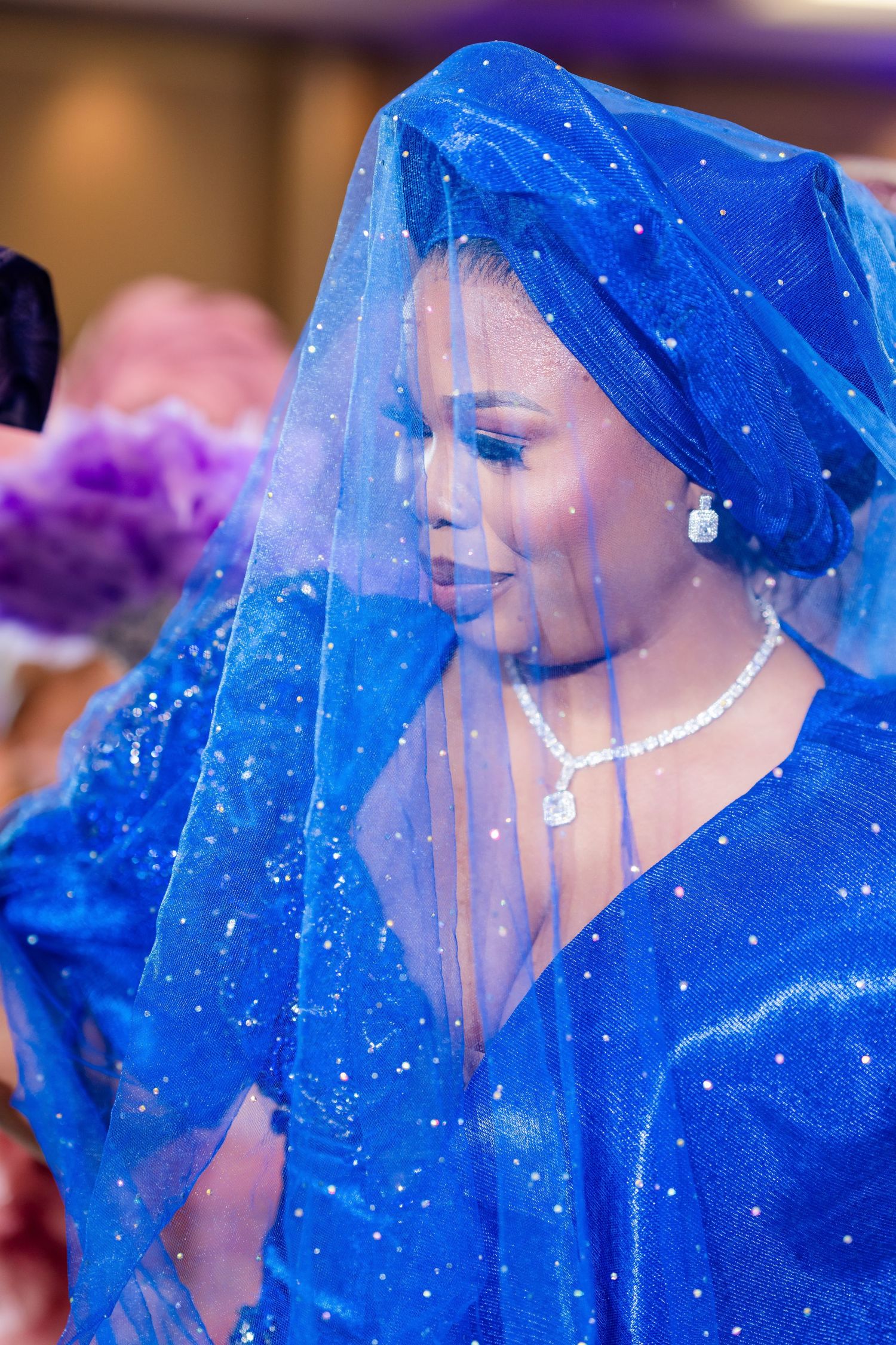 Row of attendees wearing sparkling blue formal attire with veils.