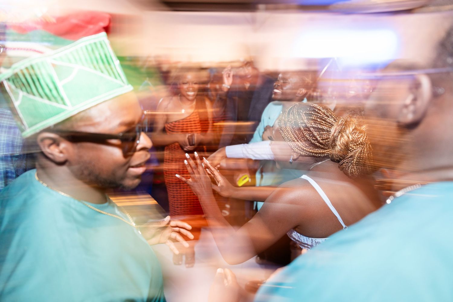 Abstract motion blur of people celebrating at a festive event with teal lighting.