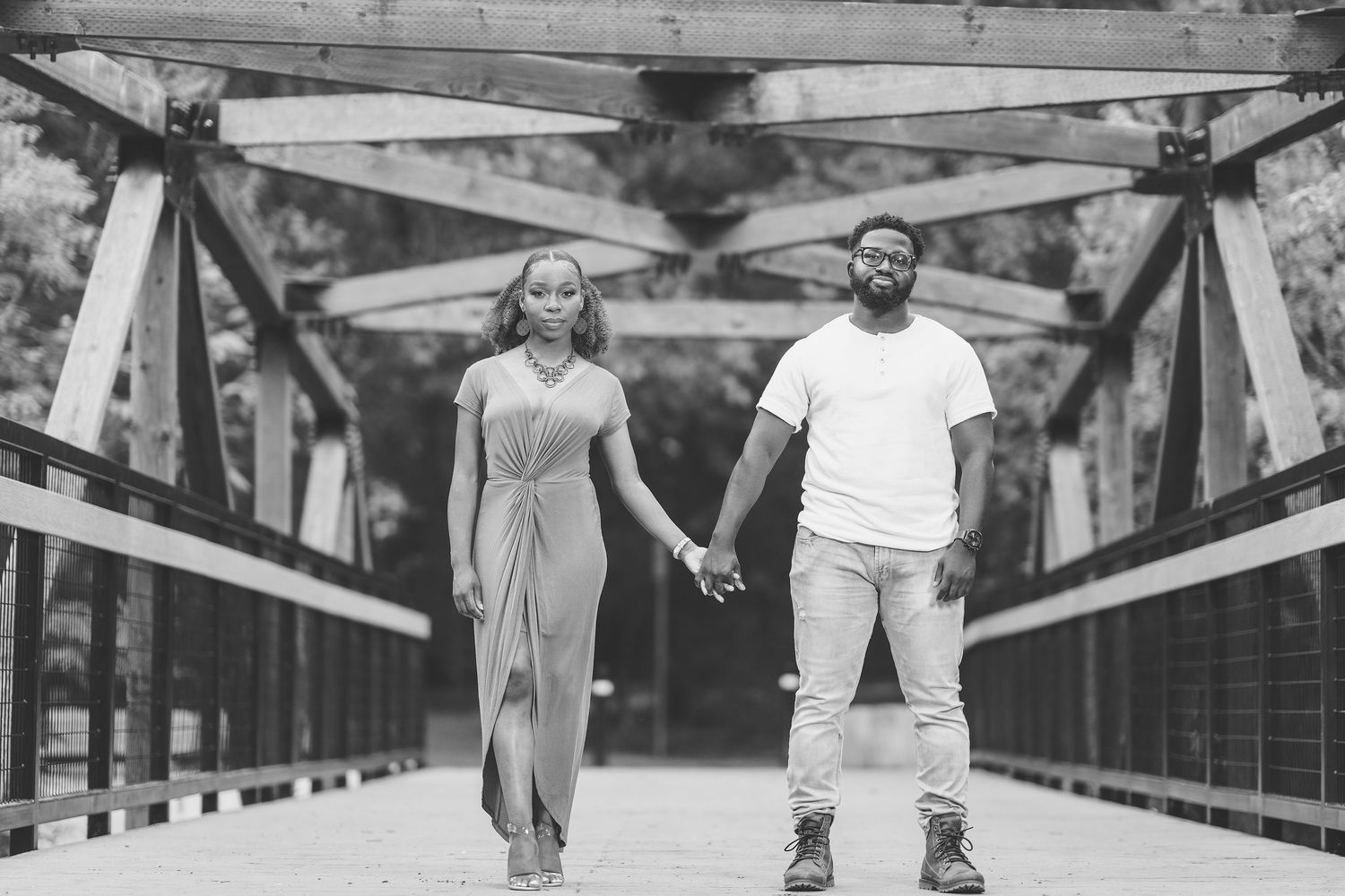 A couple enjoys a playful moment while walking on a wooden bridge structure.