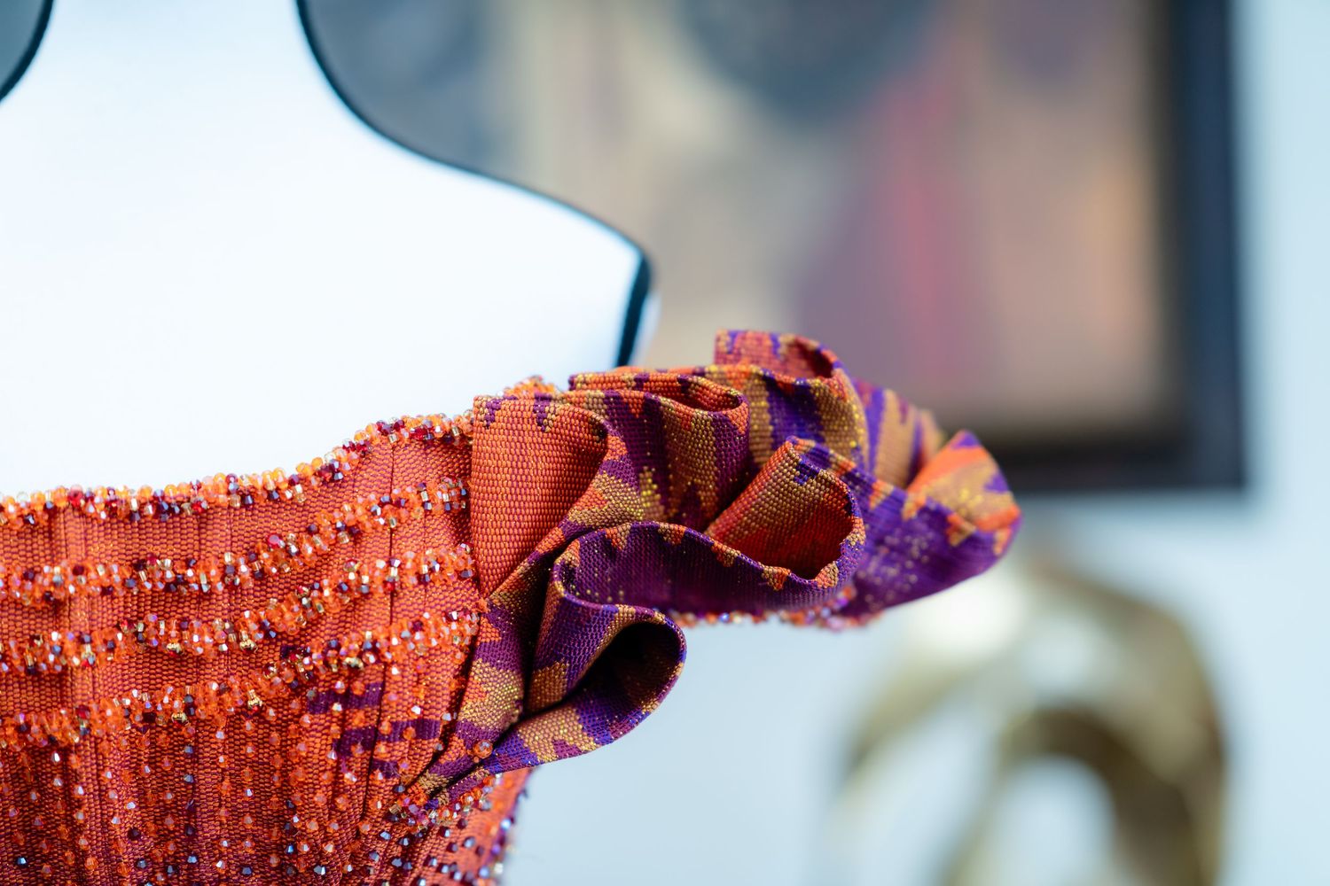 Macro detail of orange and purple beaded fabric with intricate patterns.