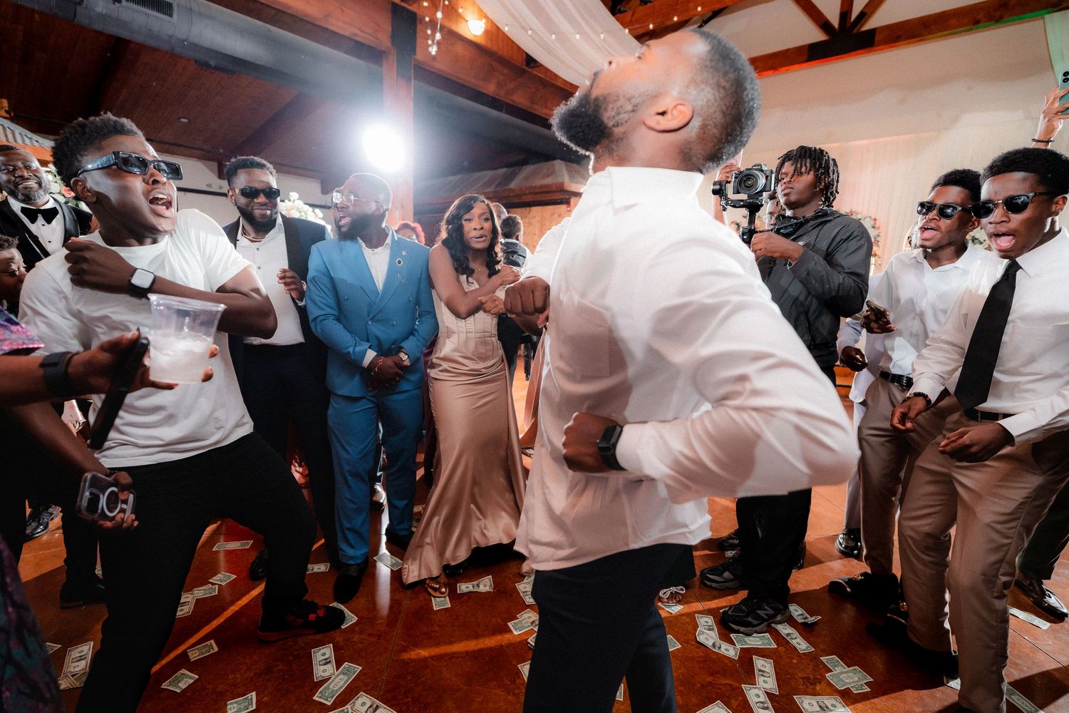 Wedding guests dancing and celebrating on reception dance floor under string lights.