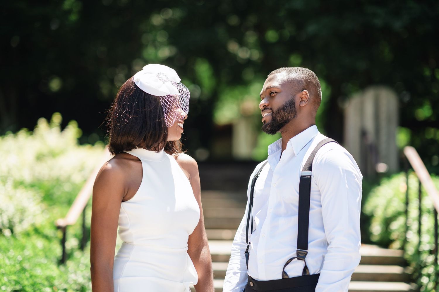 A couple shares tender moments in a sunlit garden setting wearing coordinated white and black outfits.
