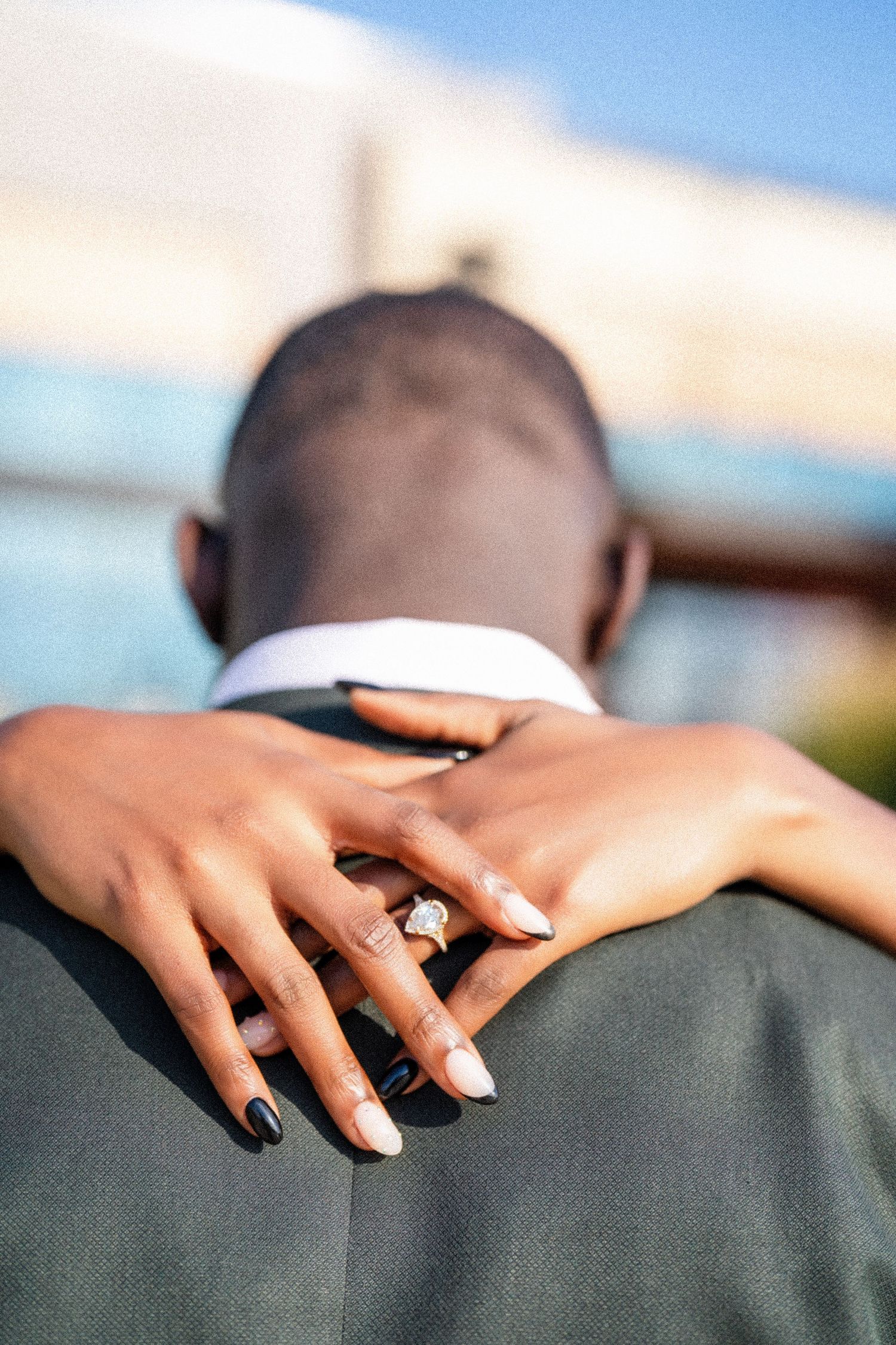 Close-up of hands with black nail polish resting on a grey suit jacket.