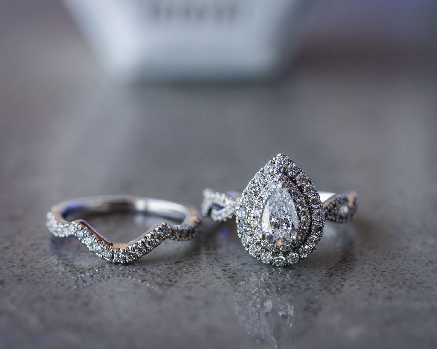 A sparkling pear-shaped diamond engagement ring with double halo setting paired with a curved wedding band.