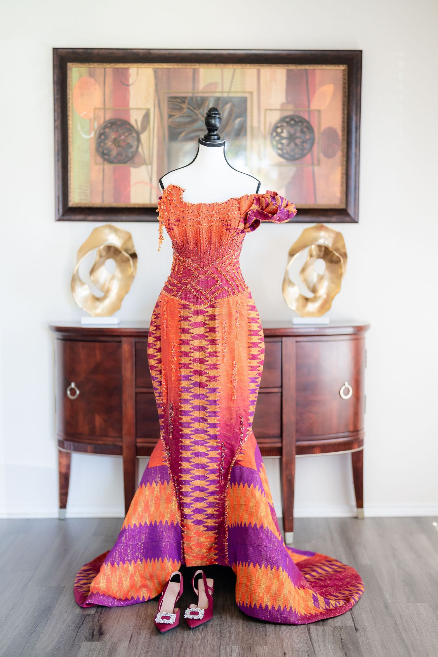 Orange and purple formal dress displayed on mannequin with intricate geometric pattern design.