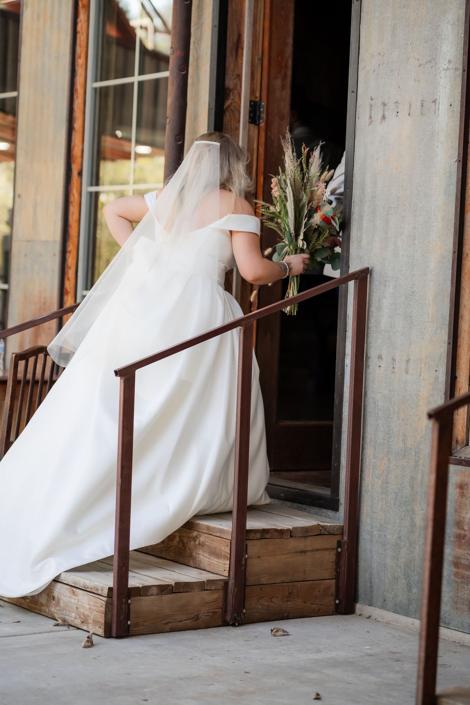 Wedding dress train flowing along rustic wooden porch with vintage details.