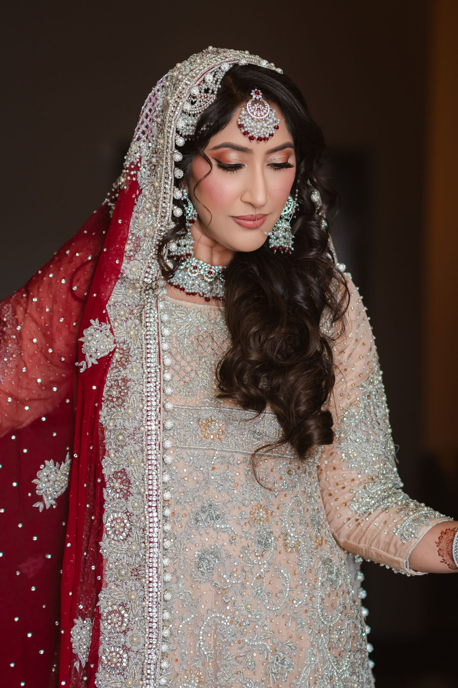 Traditional South Asian bride wearing an intricately embellished pale blue and silver lehenga with red dupatta and ornate jewelry.