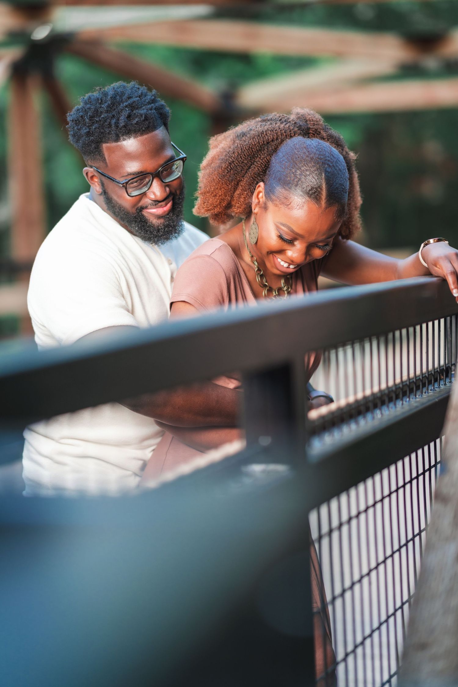 A joyful couple shares a laugh while spending time together on a bridge.