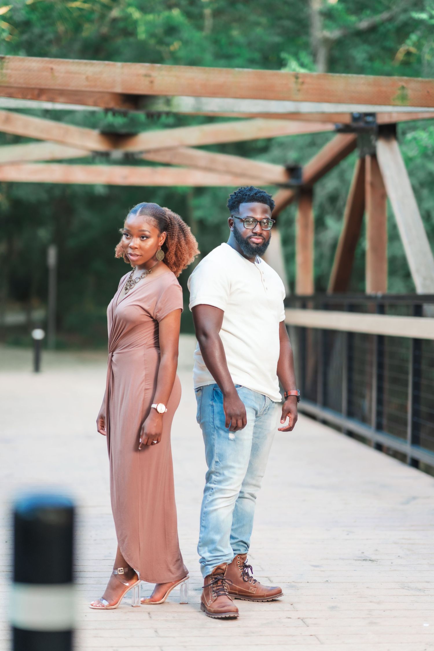 A couple walks together on a wooden bridge pathway in casual attire.