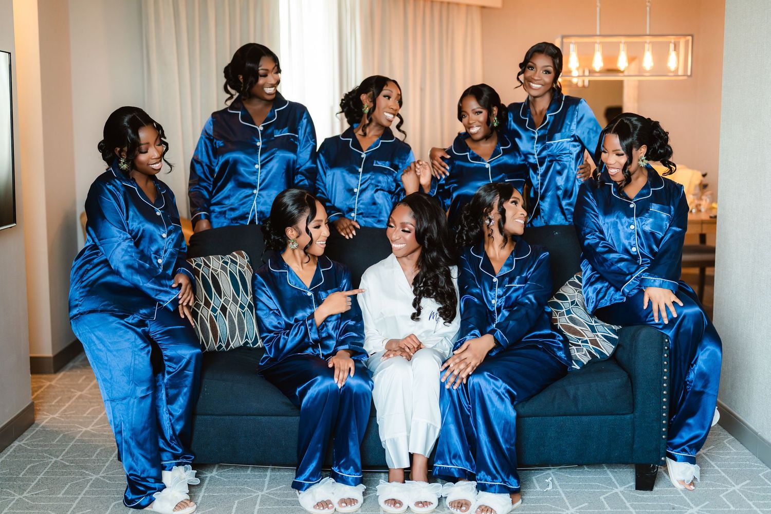 Wedding party relaxing on couches wearing matching royal blue satin robes.