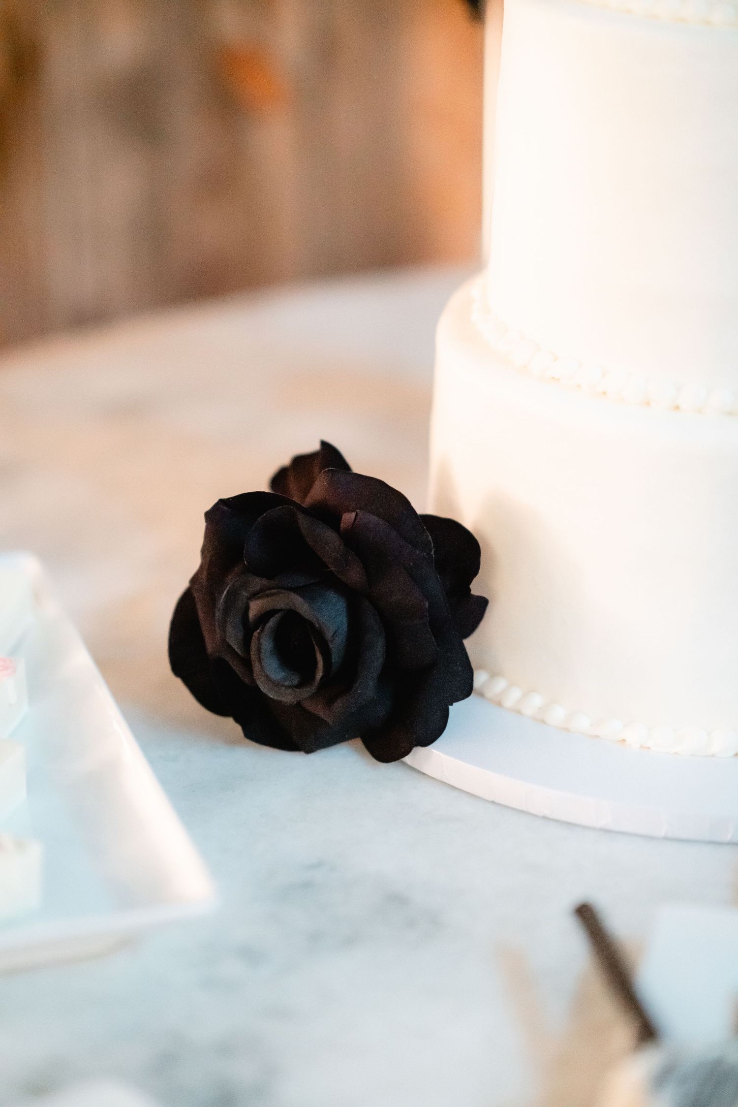 Black roses create dramatic accent details on white wedding cake.