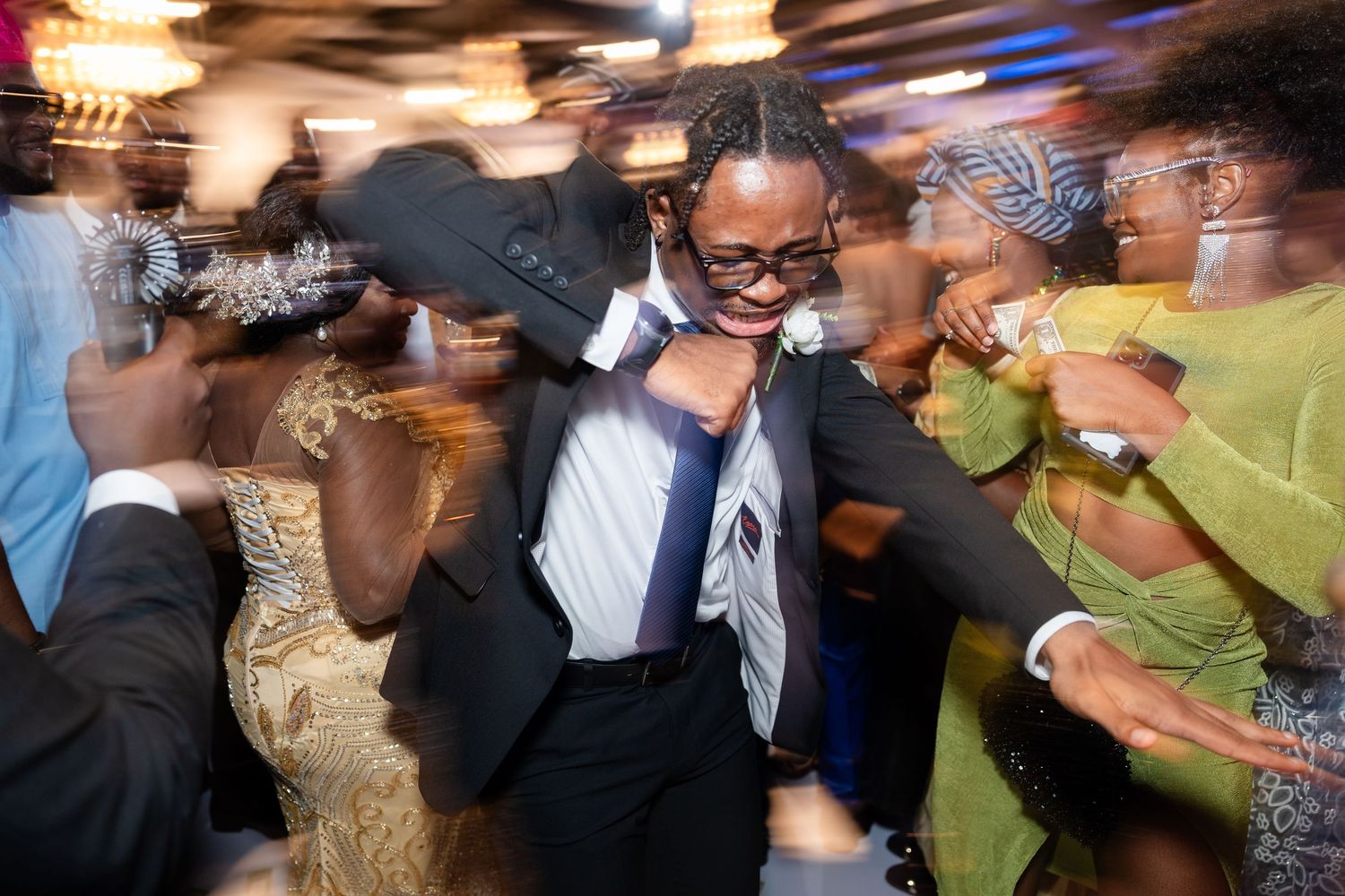 Blurred motion shot of people dancing and celebrating at a festive party with colorful lighting.