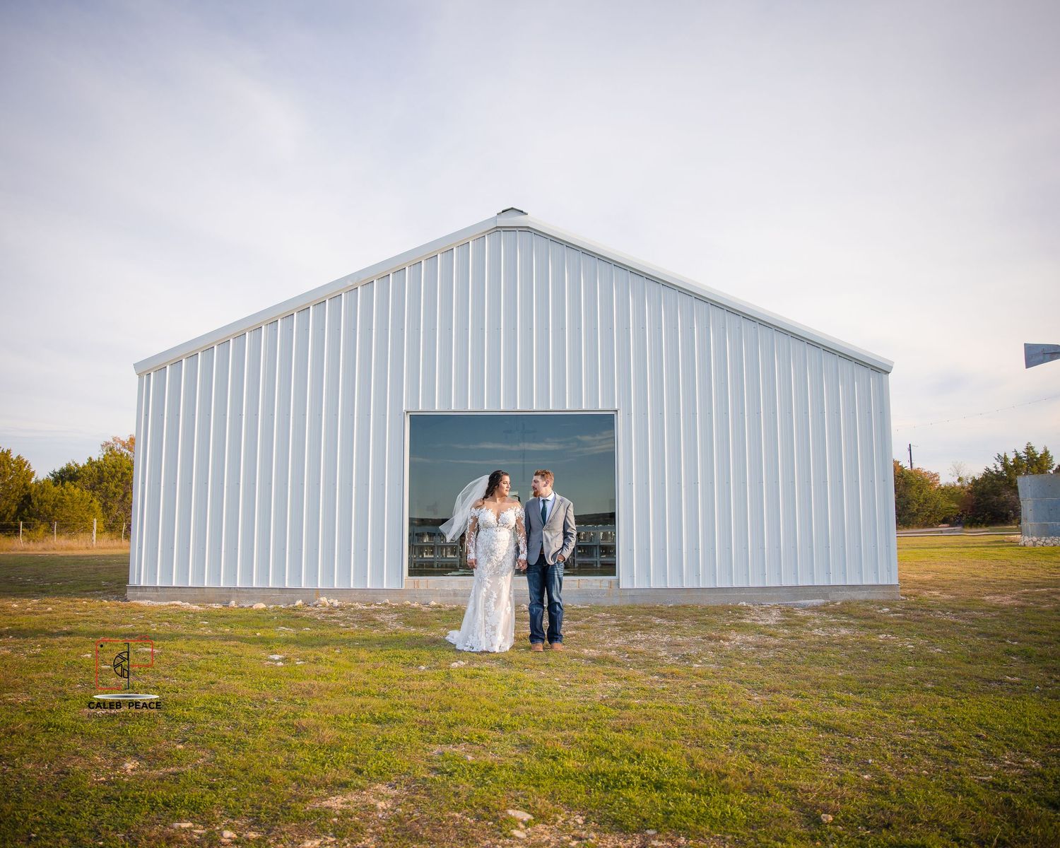 A panoramic sequence of a white barn building in a rural field during sunset.