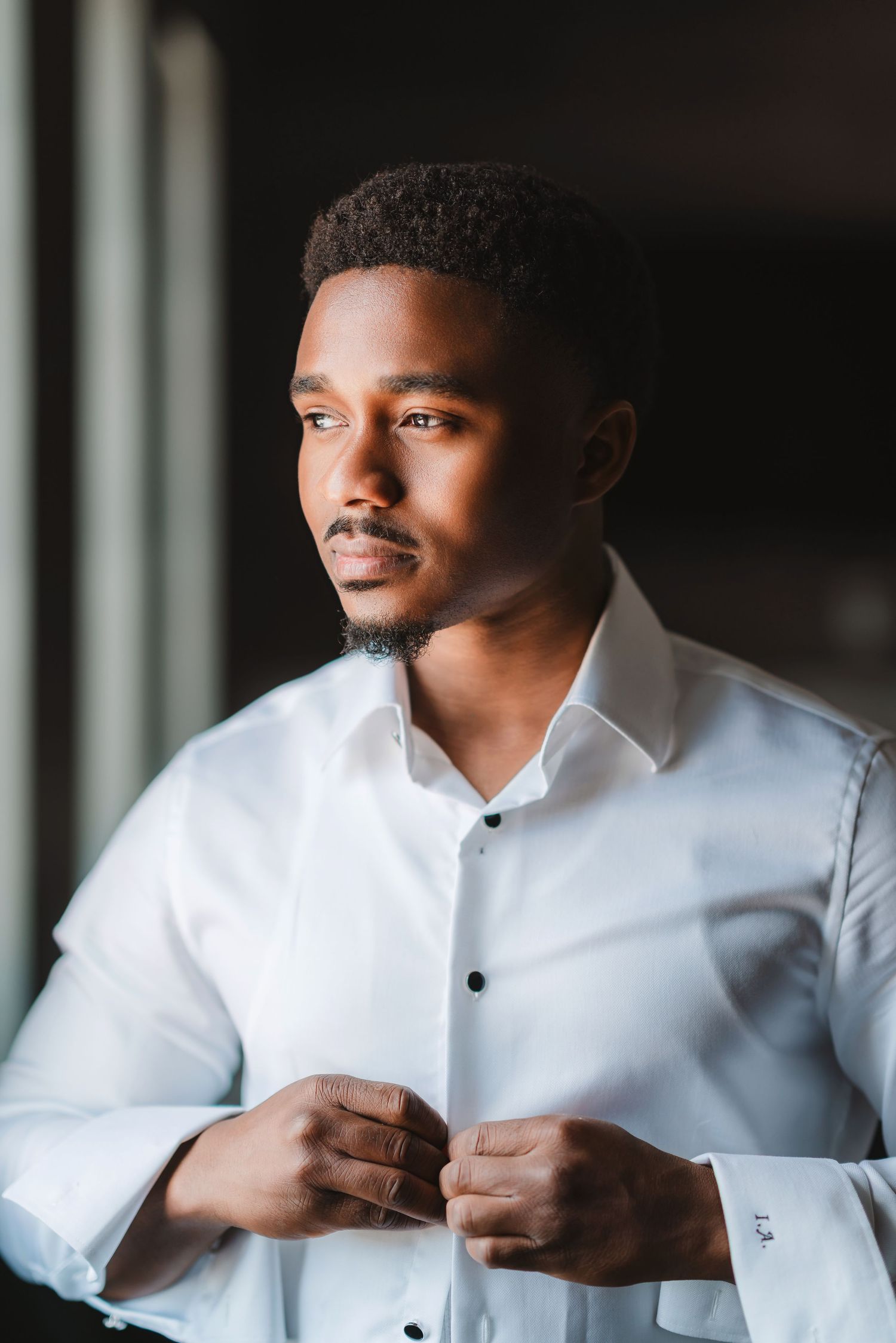 A person in a crisp white dress shirt gazes thoughtfully by a window.