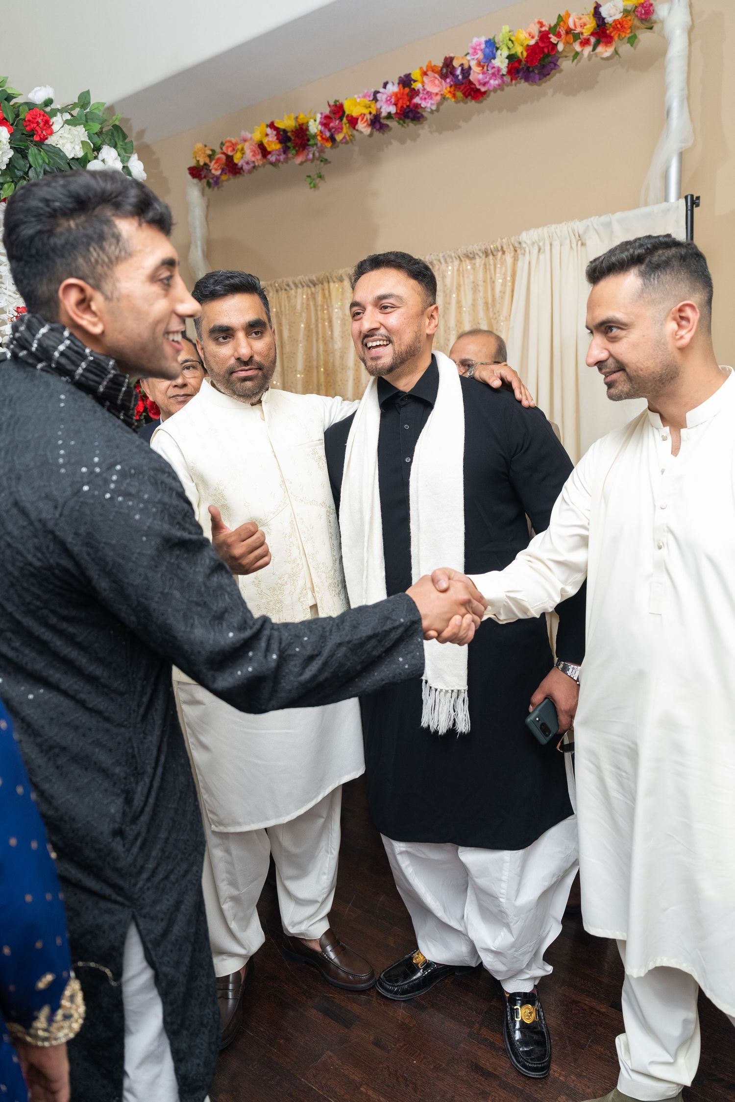 Groomsmen in white traditional outfits celebrating during wedding festivities.