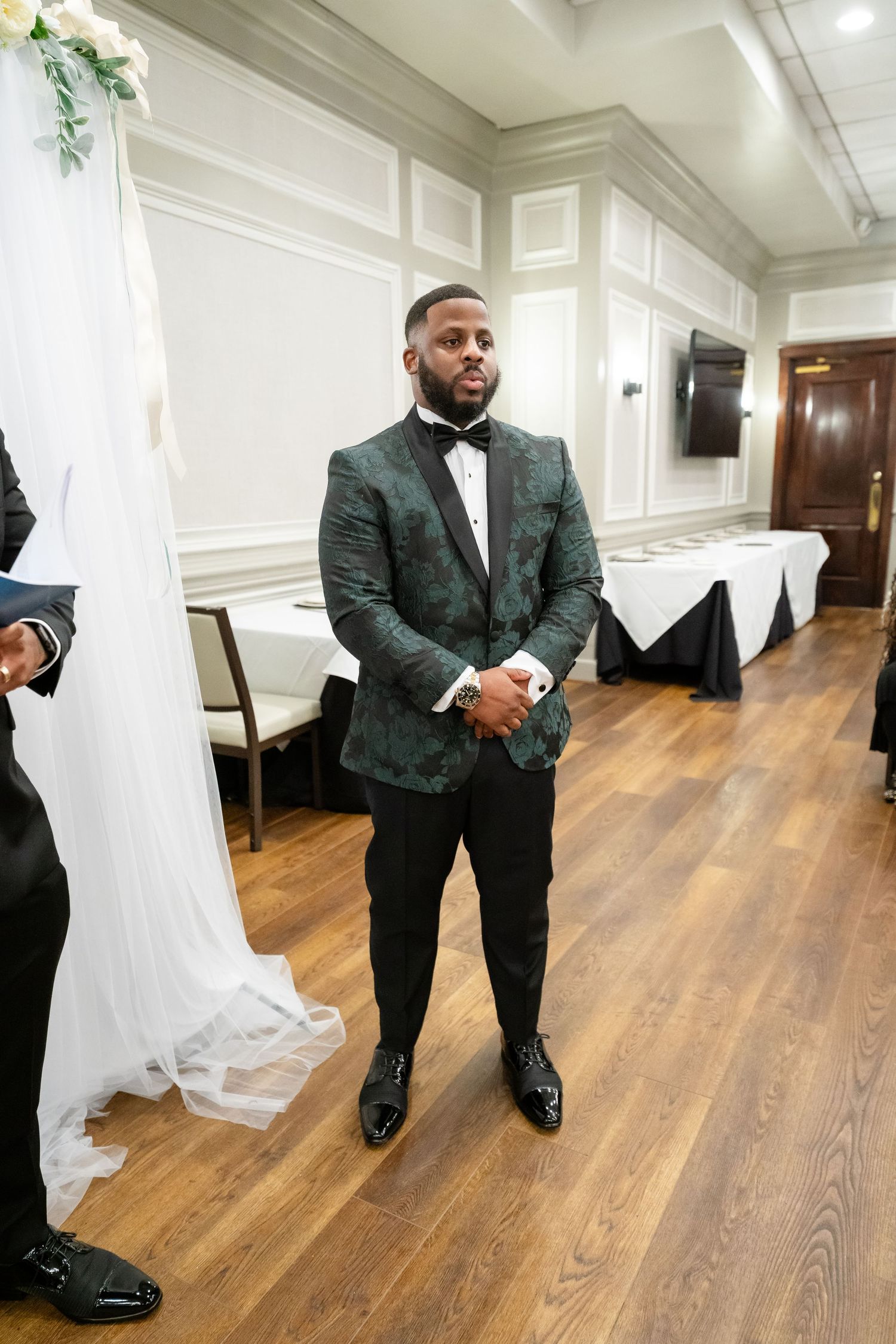 Wedding detail shots of a dark green tuxedo jacket and hardwood flooring.