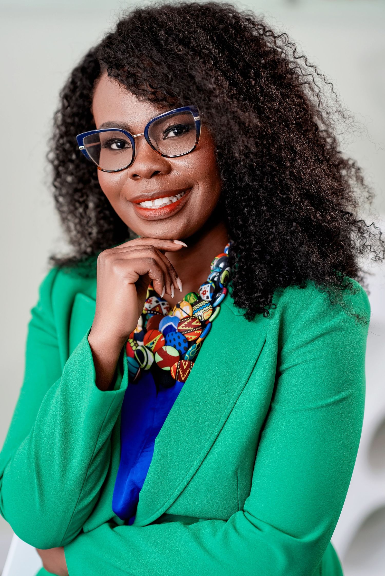 Professional portrait in bright green blazer and colorful bowtie with glasses against white background.