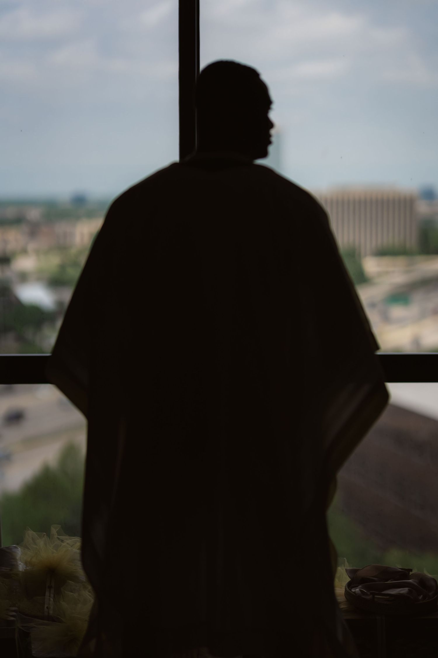 Silhouette of a person looking out a window with a cityscape view in the background.