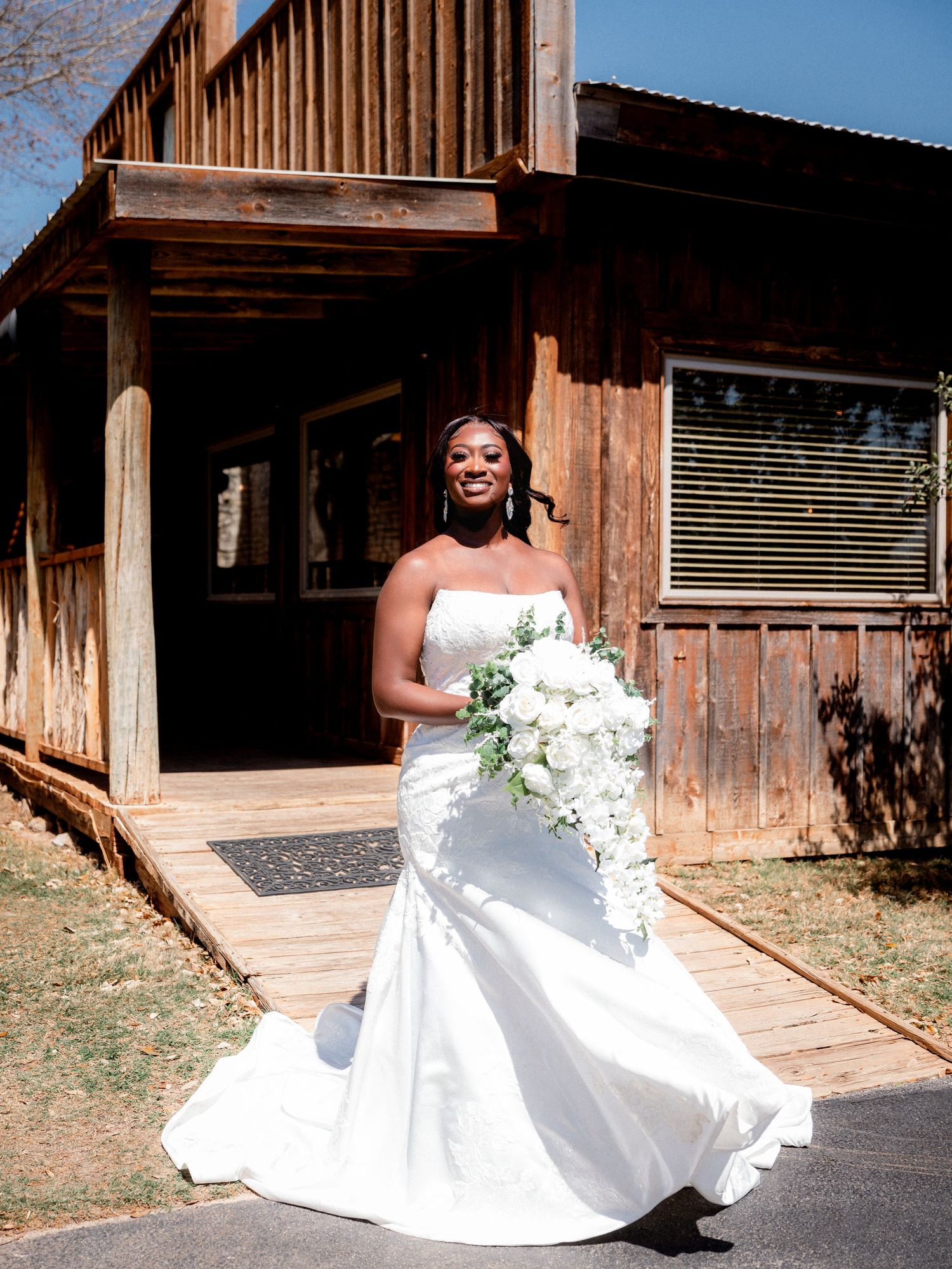 A flowing white wedding dress photographed against rustic wooden barn walls.