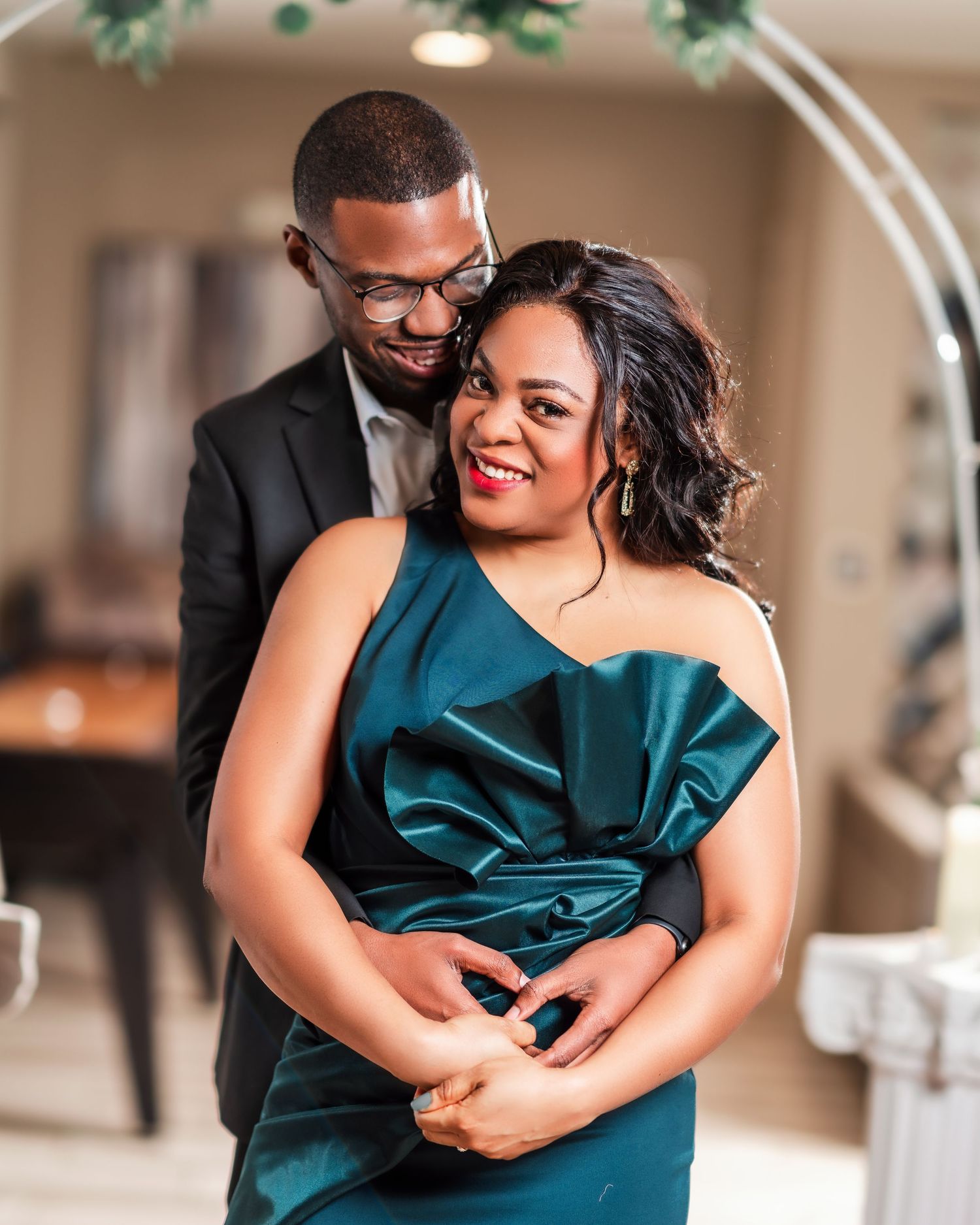 A couple embraces in matching emerald green formal attire during a romantic photoshoot.