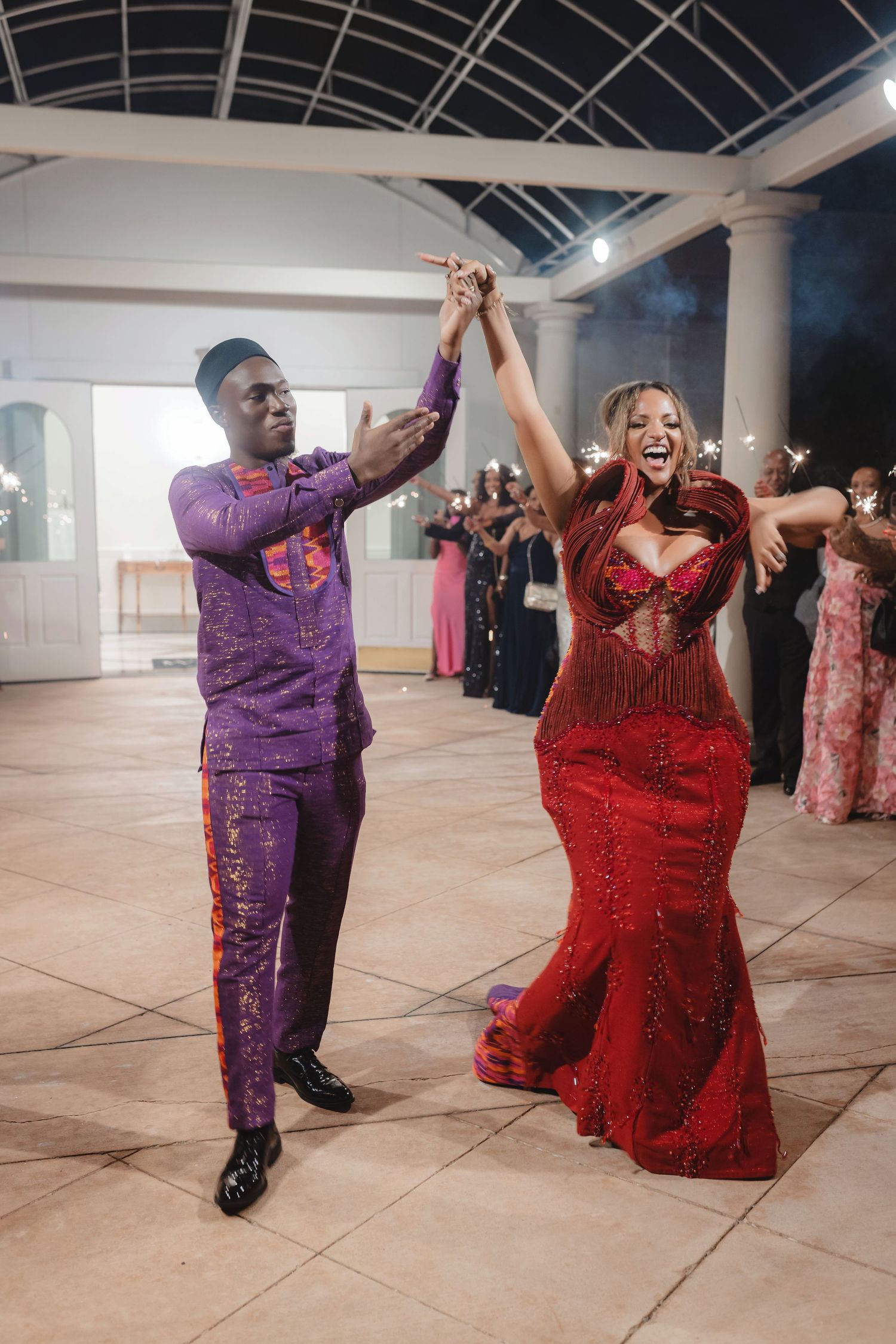 Two dancers in sparkling formal attire perform energetic dance moves in a bright studio space.