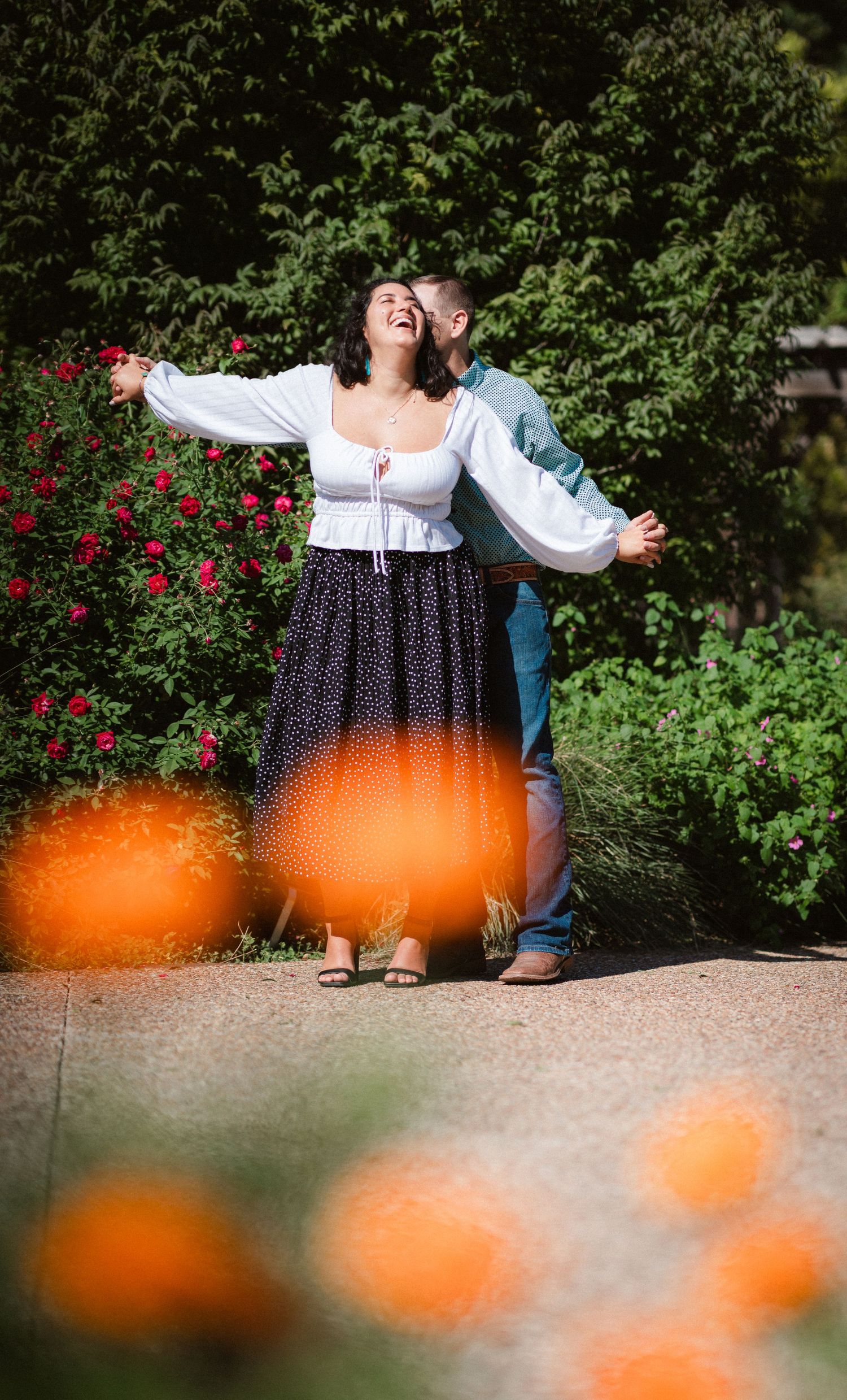 A joyful moment in a garden with orange poppies in the foreground and red roses behind.