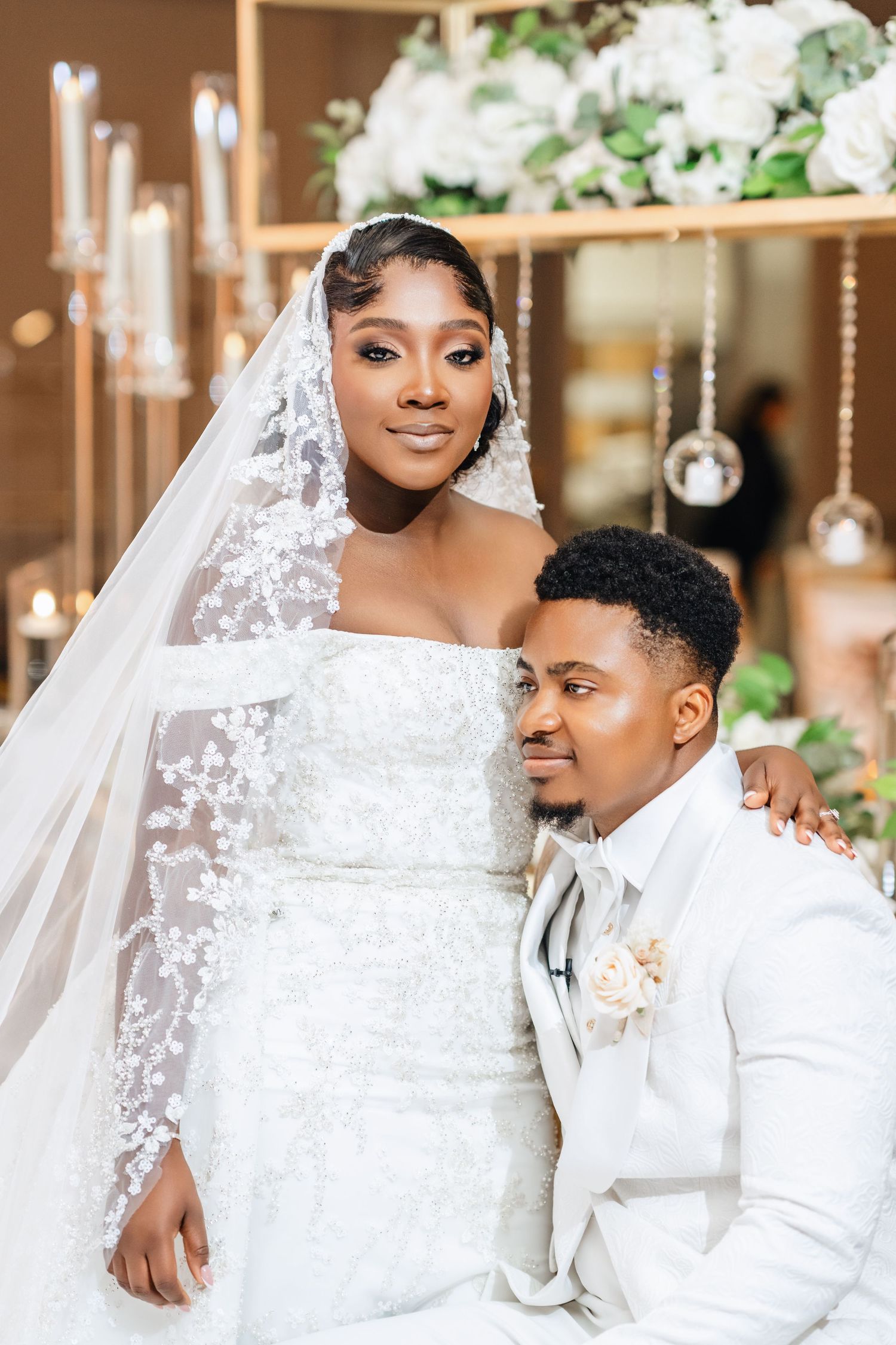 Romantic wedding portrait of couple in white attire with elegant decor.