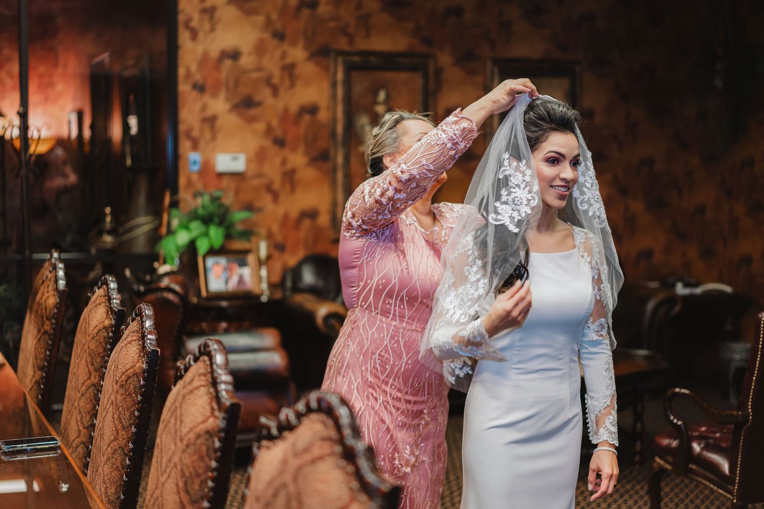 A bride in white dress dances joyfully in a warmly lit indoor setting.