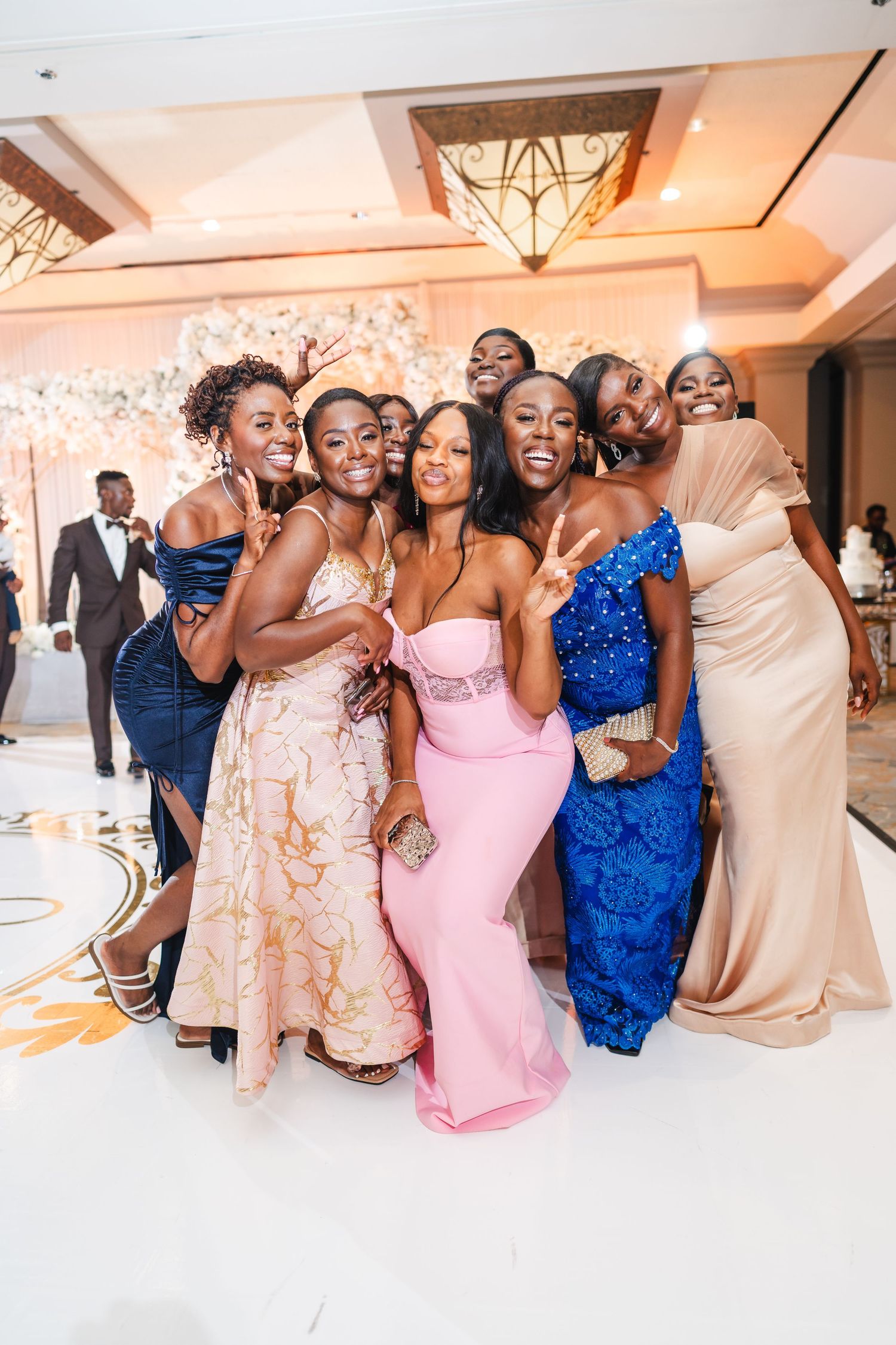 Wedding reception celebration with guests in pink and blue formal attire dancing and posing together.